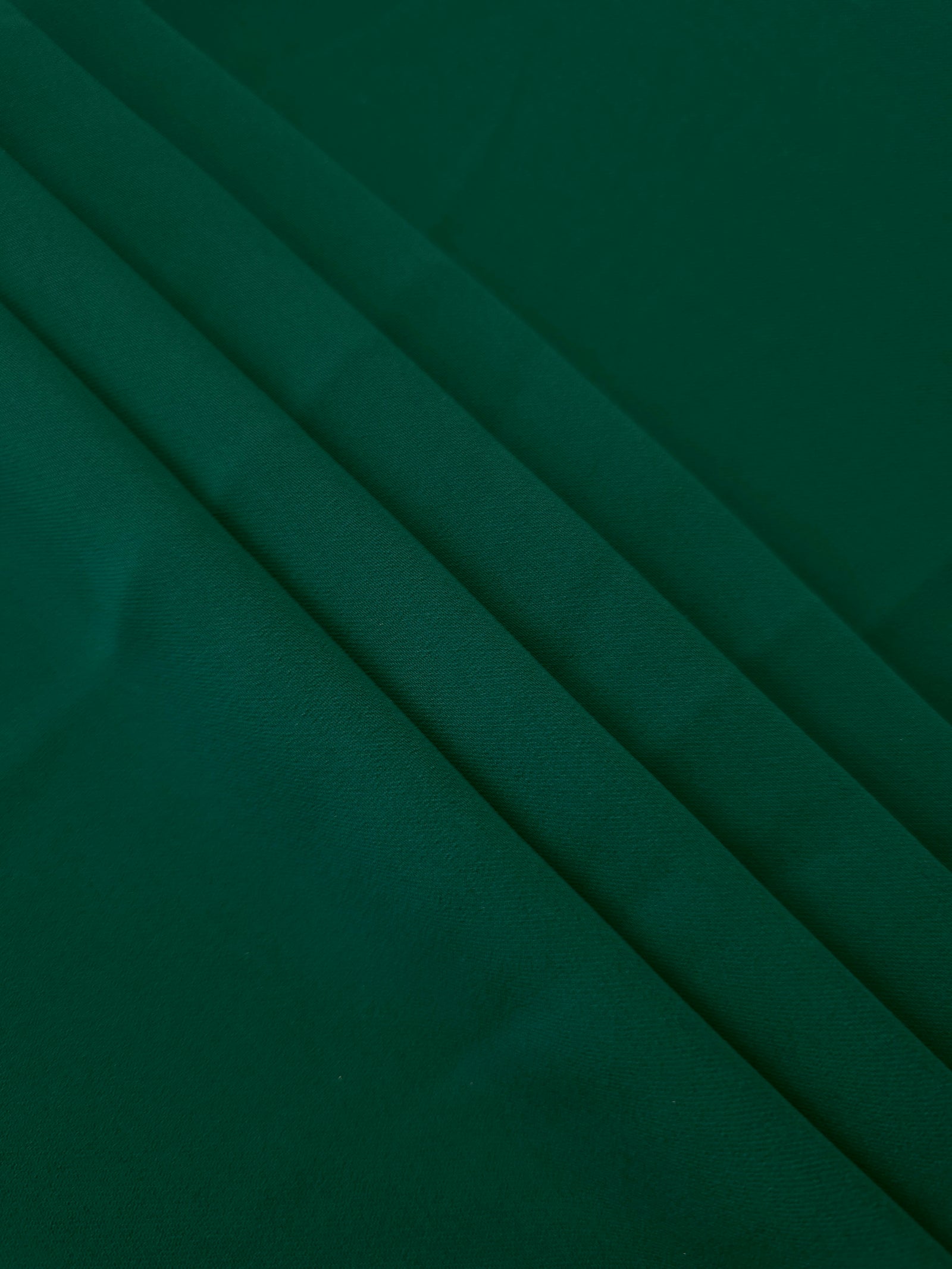 Layered Deep Emerald Green Korean polyester crepe showing gentle mechanical stretch and soft structure for dressmaking