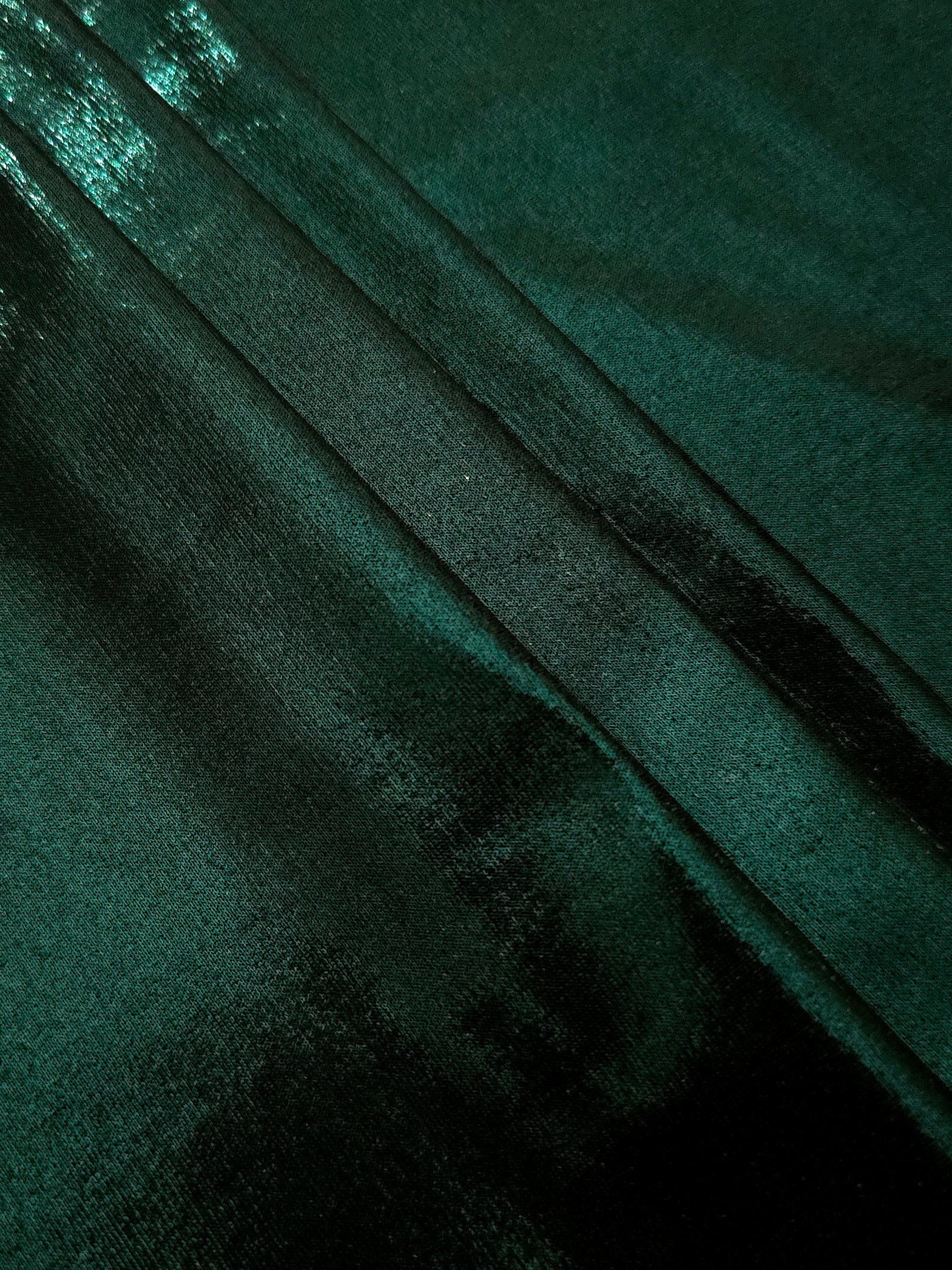 Deep Emerald Green metallic foiled spandex in layered folds, highlighting reflective texture and flexible structure for stage and eveningwear