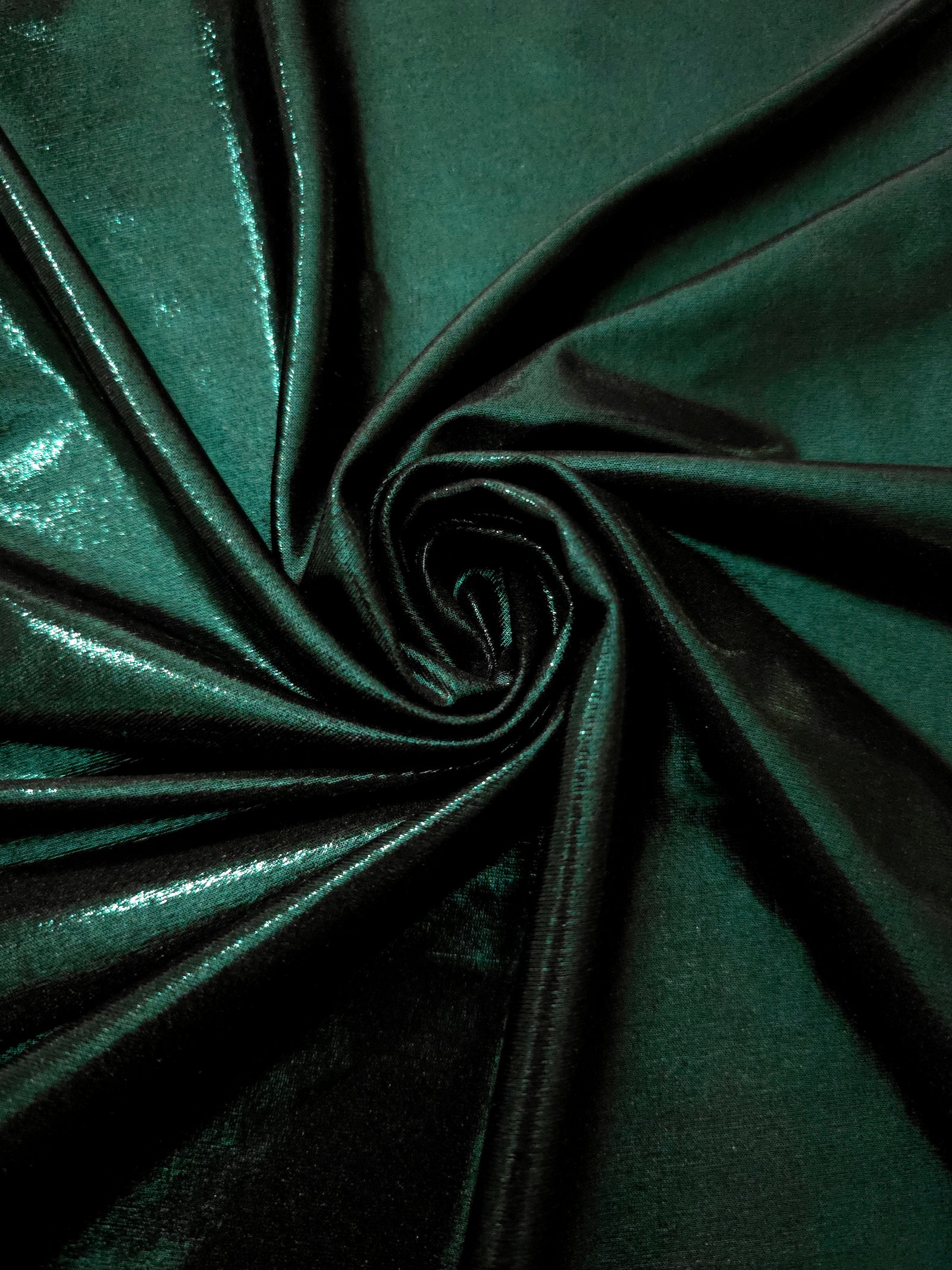 Swirled Deep Emerald Green metallic foiled spandex showing fluid movement and luminous sheen for dresses, dancewear and stage costumes