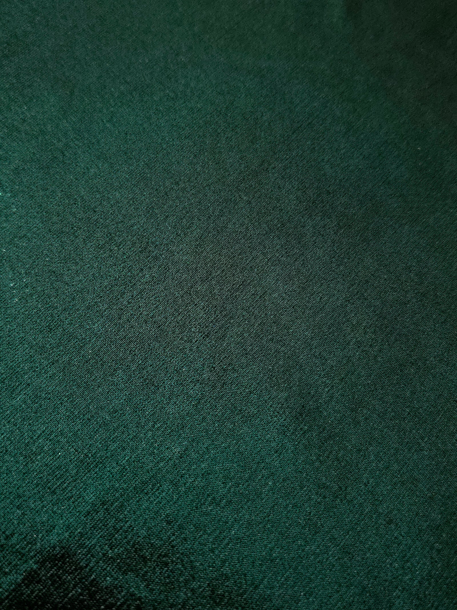 Deep Emerald Green shimmer stretch fabric close-up, revealing metallic foil texture and reflective detail for fashion and costume sewing