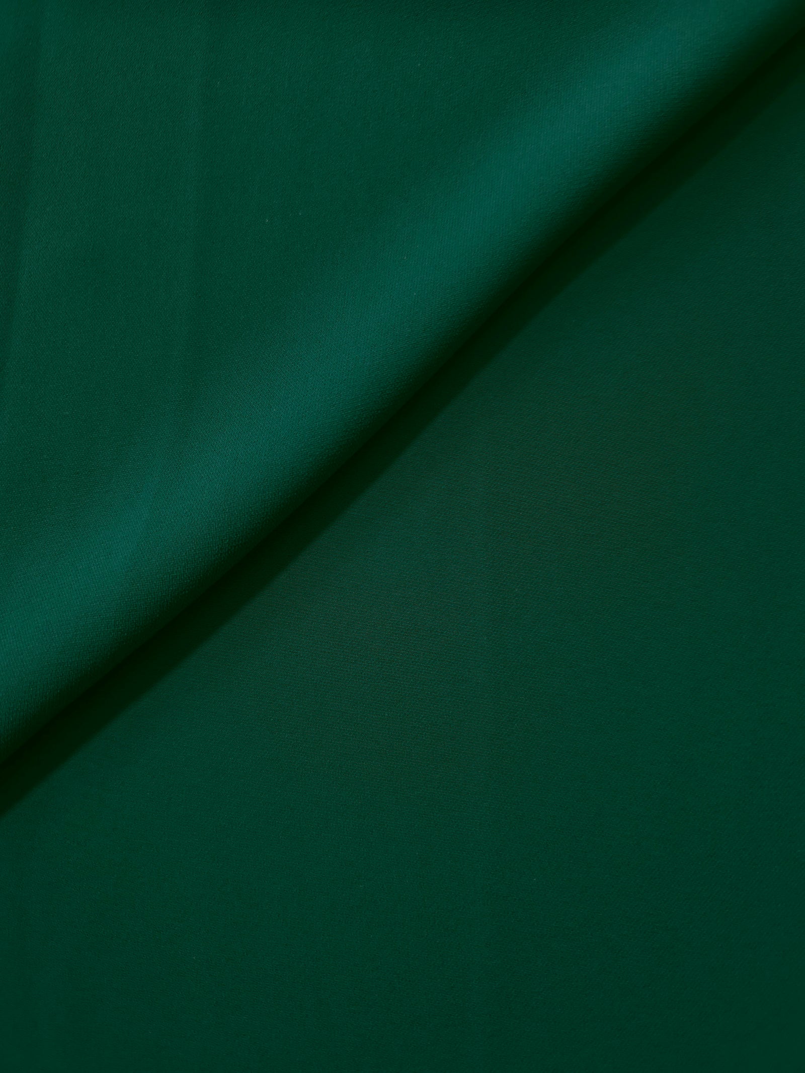 Deep Emerald Green opaque Korean polyester crepe in a soft fold, showing flowing drape for garment making