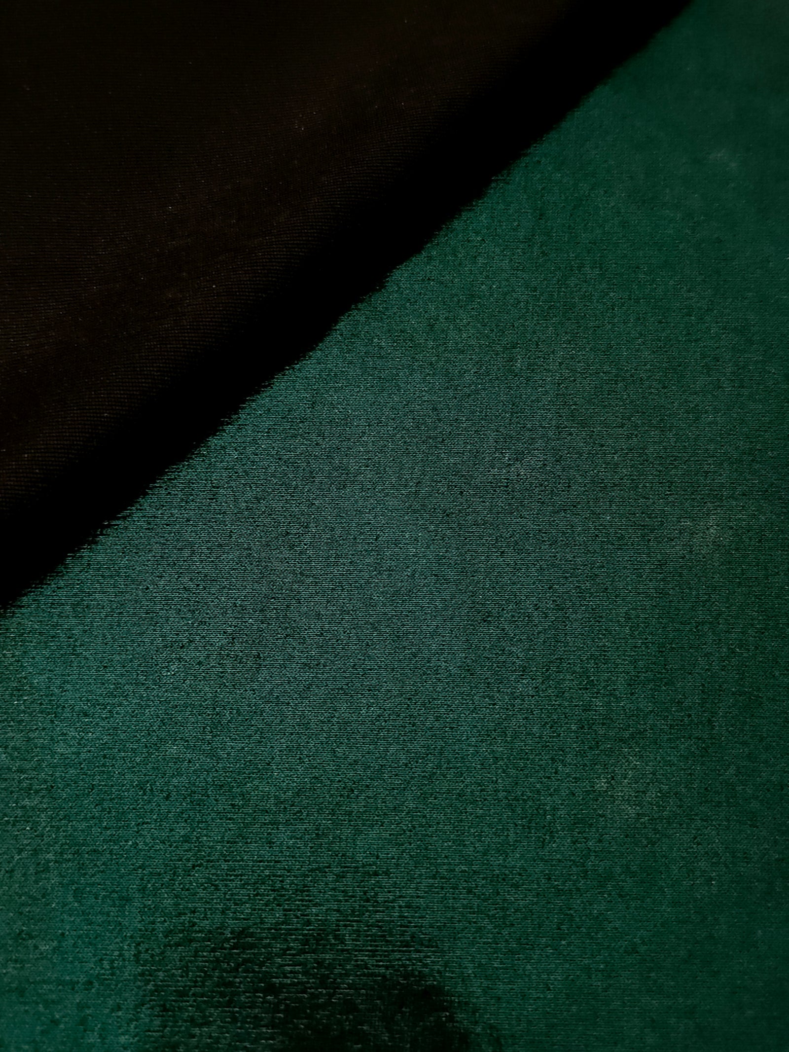 Soft fold of Deep Emerald Green metallic foiled spandex highlighting reflective sheen and supple movement for dresses and stagewear