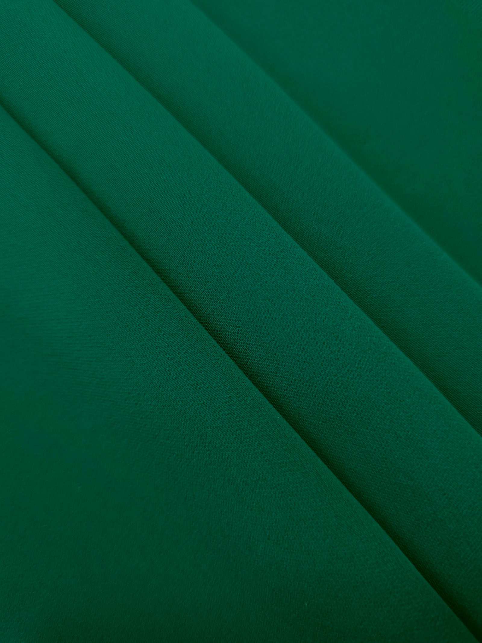 Layered Deep Jade Green Korean polyester crepe showing gentle mechanical stretch and soft structure for dressmaking