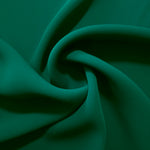 Deep Jade Green silky-soft polyester crepe styled in a swirl to show fluid dressmaking drape and movement