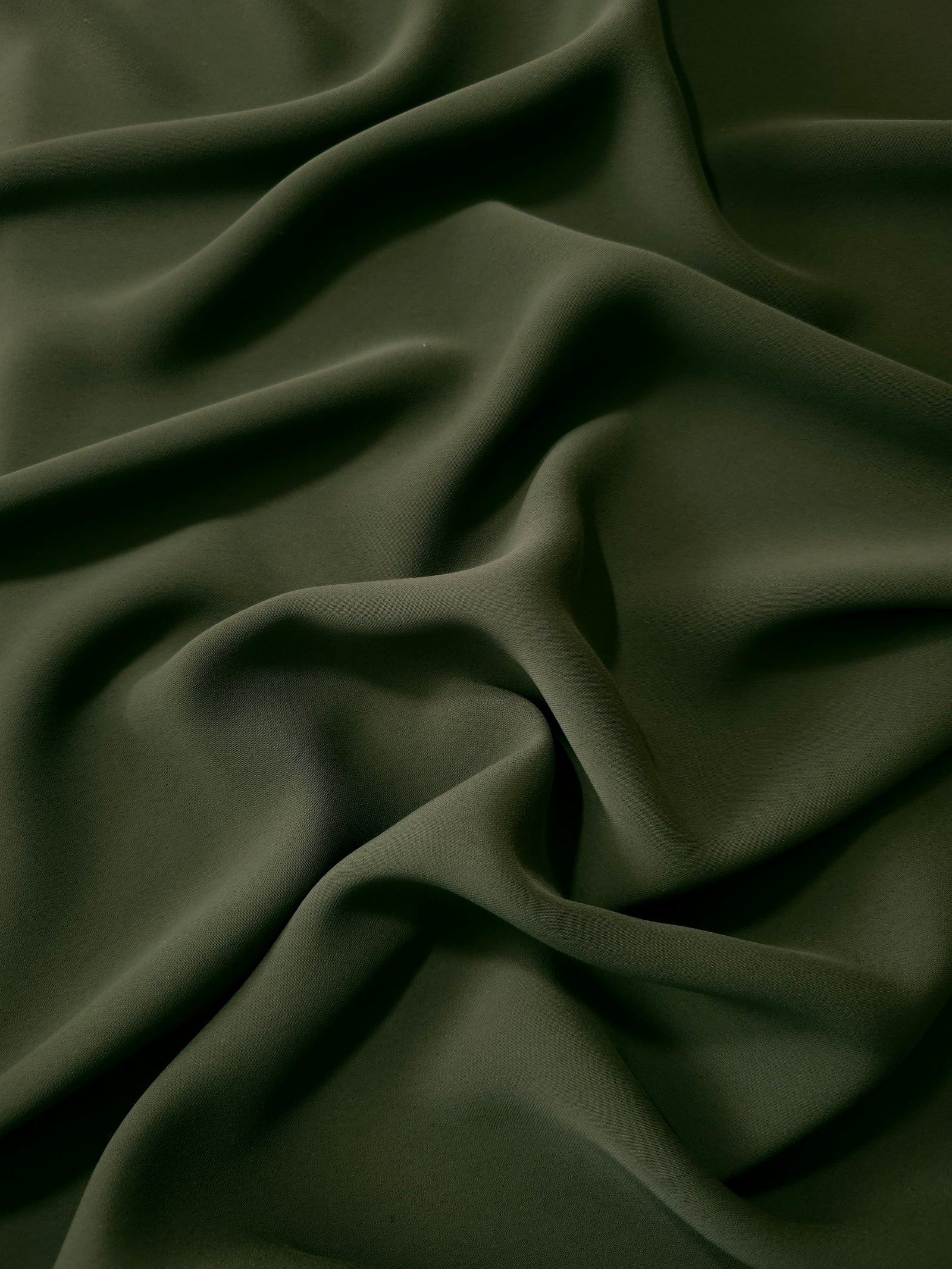 Deep Olive Green Korean polyester dress fabric shown in draped folds for occasionwear, blouses and dresses