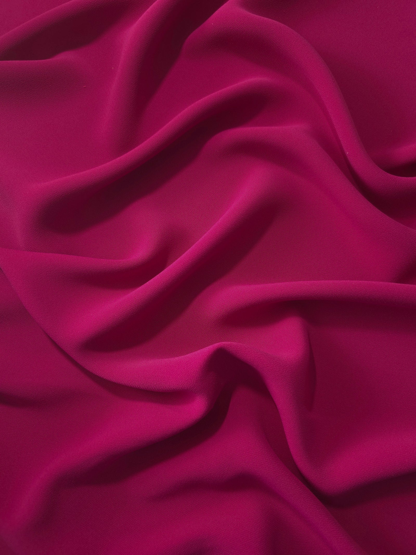 Deep Raspberry Pink Korean polyester crepe in a soft fold, showing fluid drape for blouses and flowing dresses