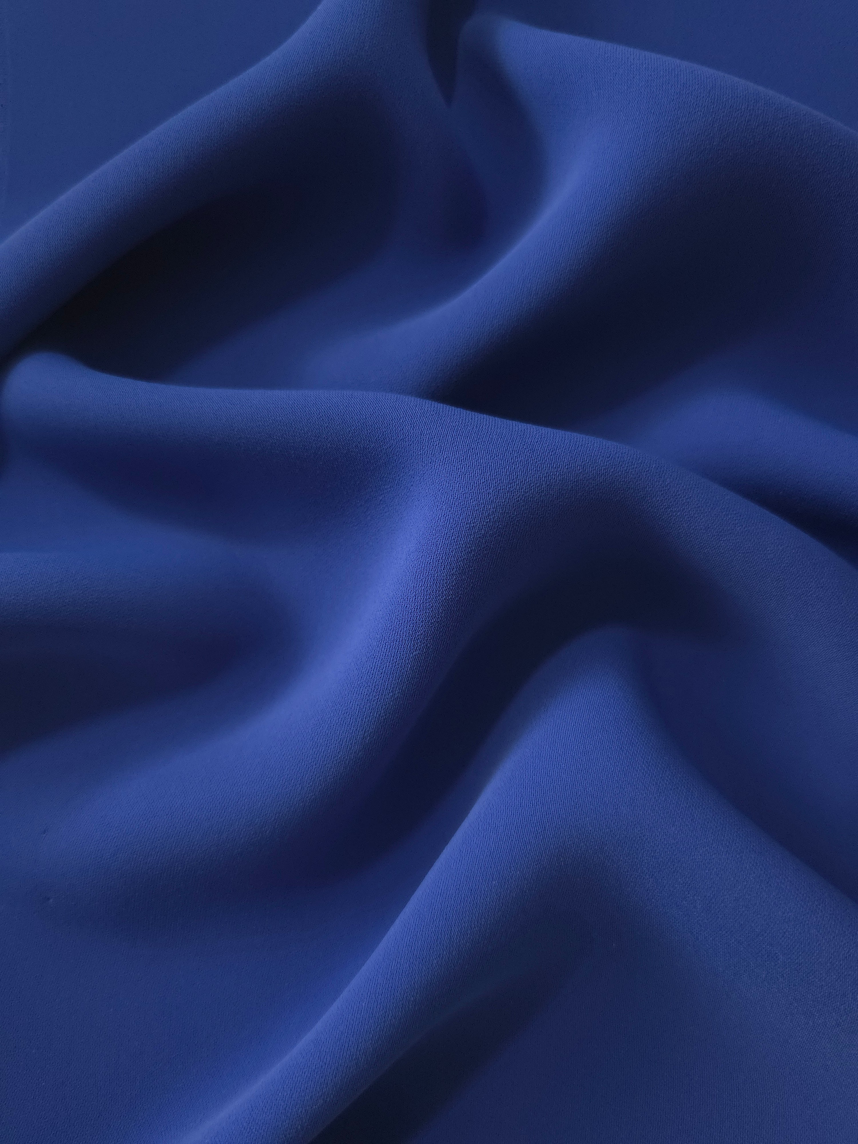 Deep Royal Blue Italian polyester crepe shown in draped folds for occasionwear, blouses and elegant dresses