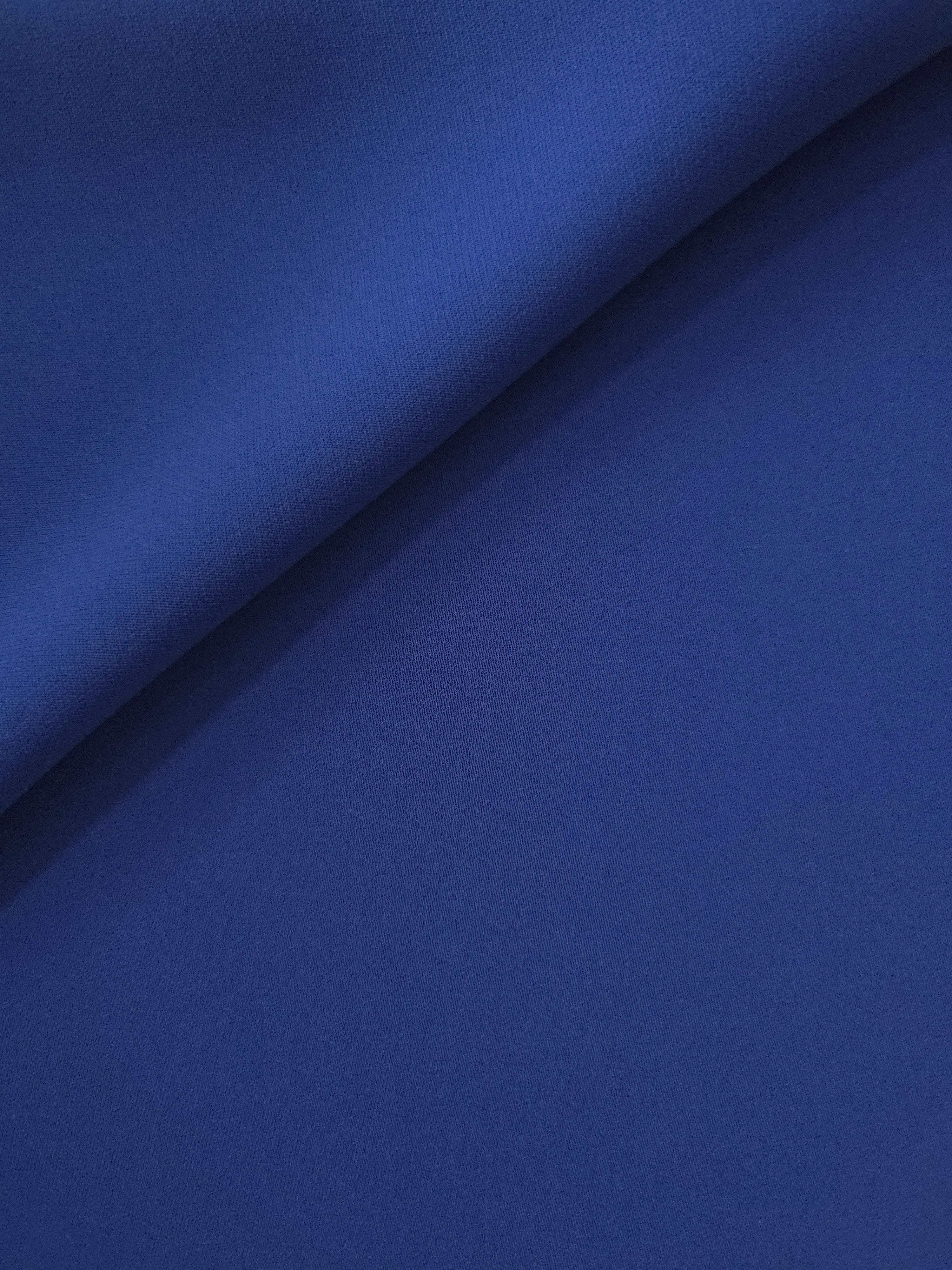 Loose fold of Deep Royal Blue polyester crepe showing fluid drape for dresses, skirts and soft tailoring