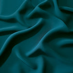 Draped folds of Deep Teal polyester crepe showing opaque coverage and fluid movement for garment making