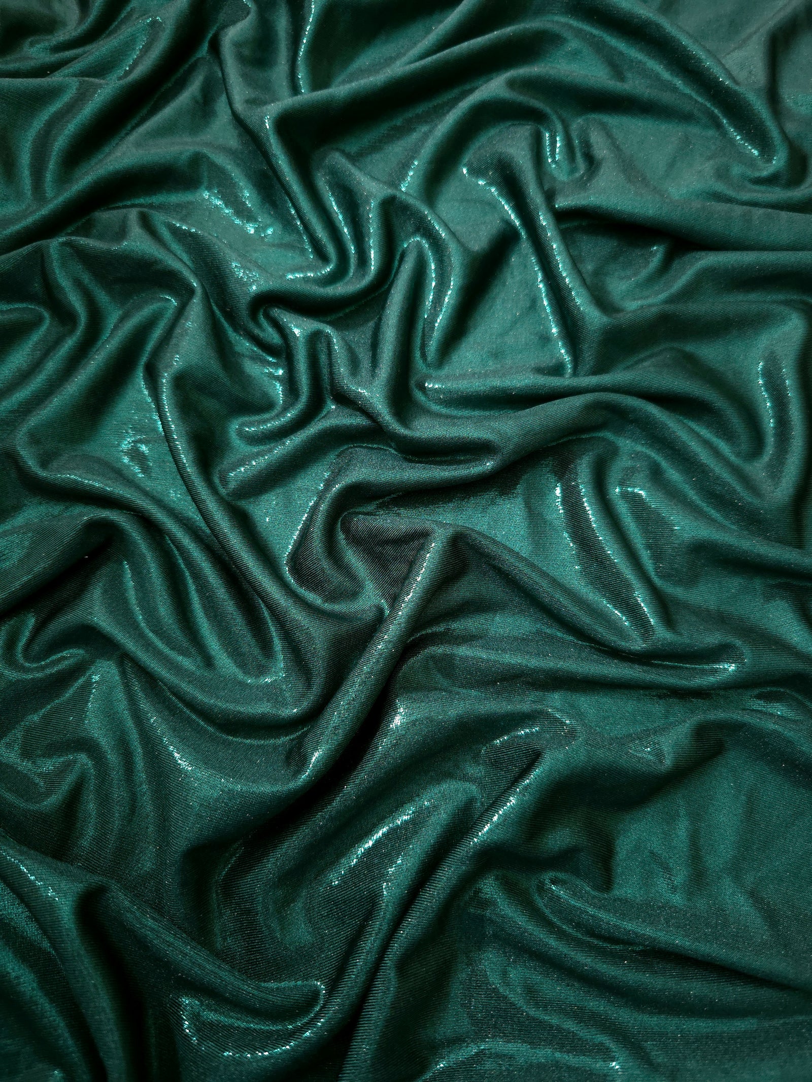 Draped Deep Teal Green metallic foiled spandex showing reflective folds and flexible flow for dresses, stagewear and occasion looks