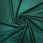 Deep Teal Green shimmer foiled stretch fabric arranged in a swirl, highlighting movement and reflective finish for performancewear