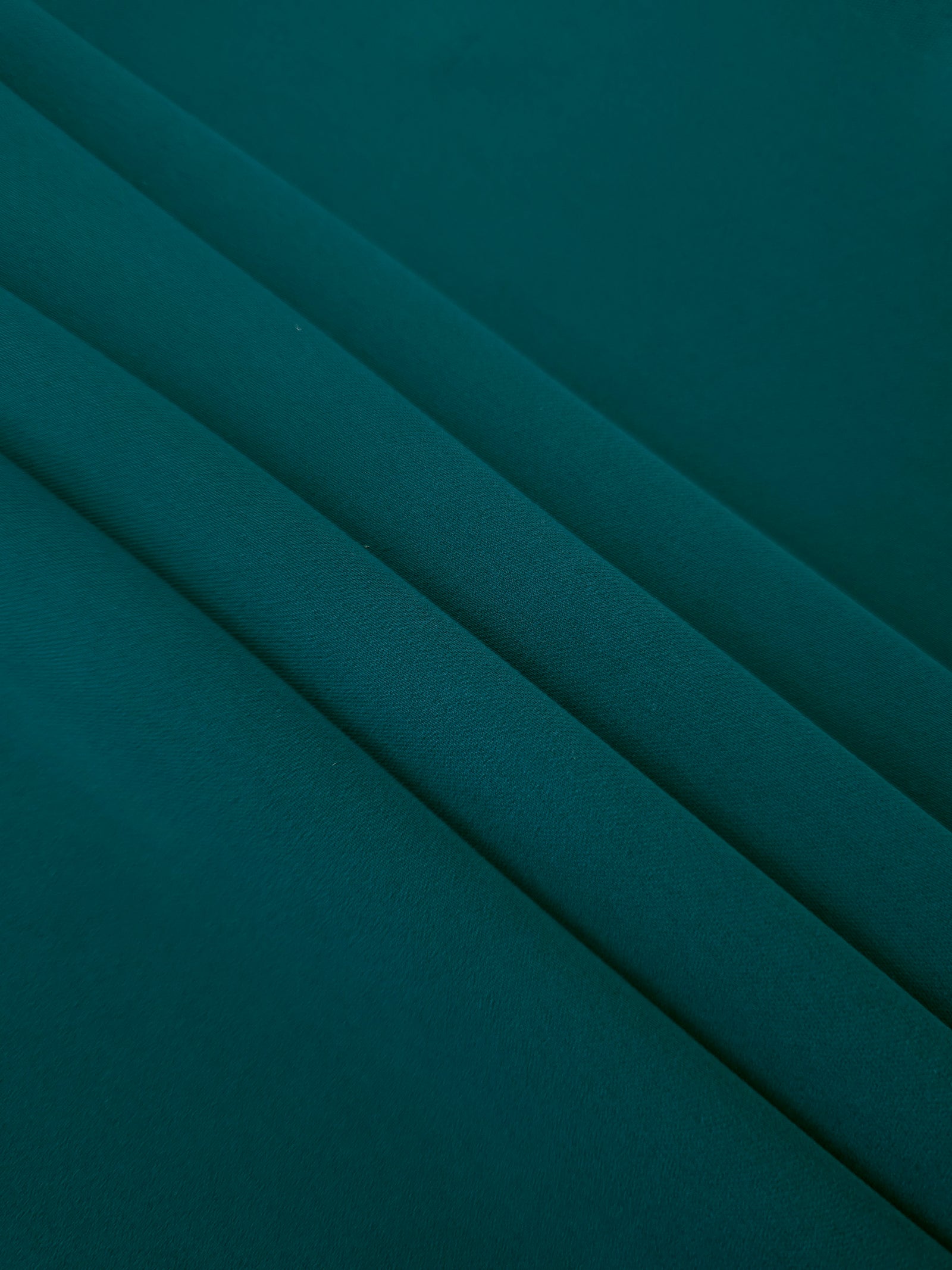 Layered Deep Teal Korean polyester crepe showing gentle mechanical stretch and soft structure for dressmaking
