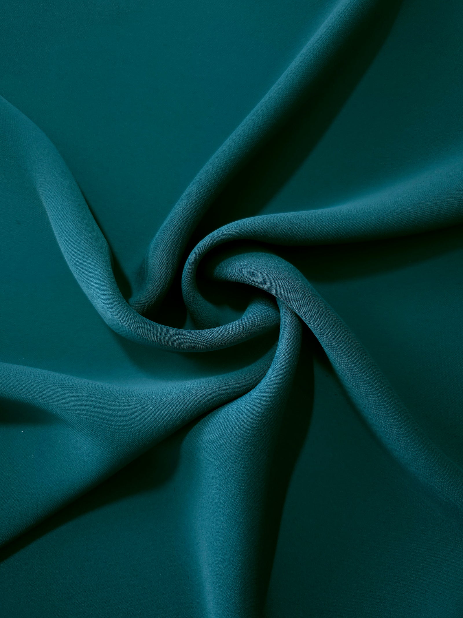 Deep Teal silky-soft polyester crepe styled in a swirl to show fluid dressmaking drape and movement