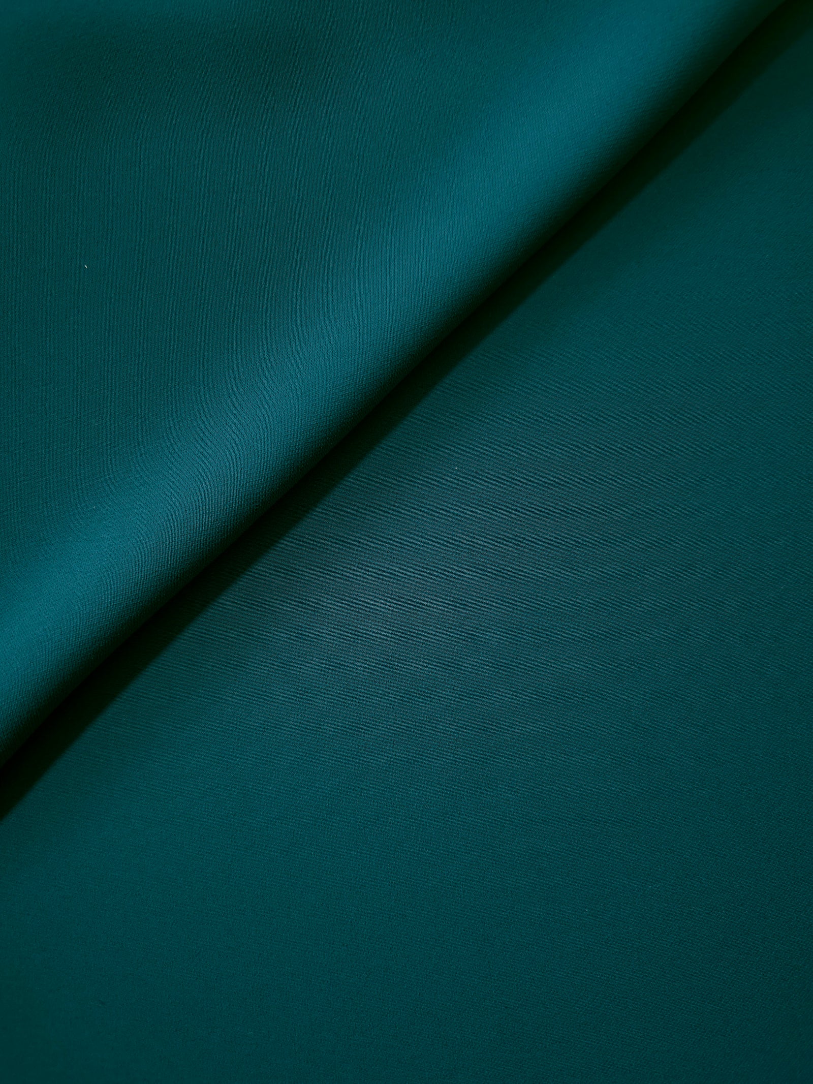 Deep Teal opaque Korean polyester crepe in a soft fold, showing flowing drape for garment making