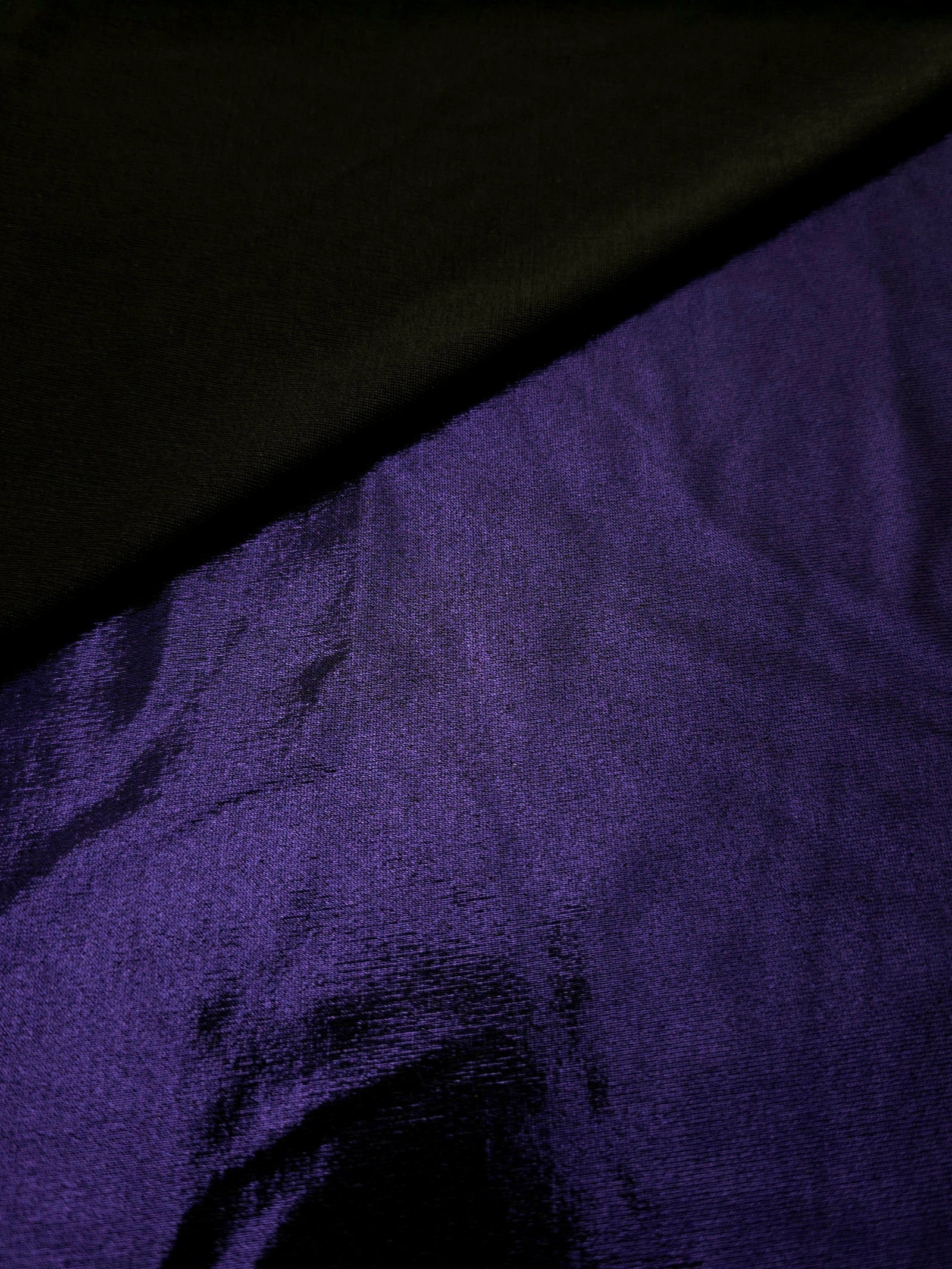 Gently folded Deep Violet Purple shimmer spandex fabric showing luminous foil finish for tops, skirts and occasion garments