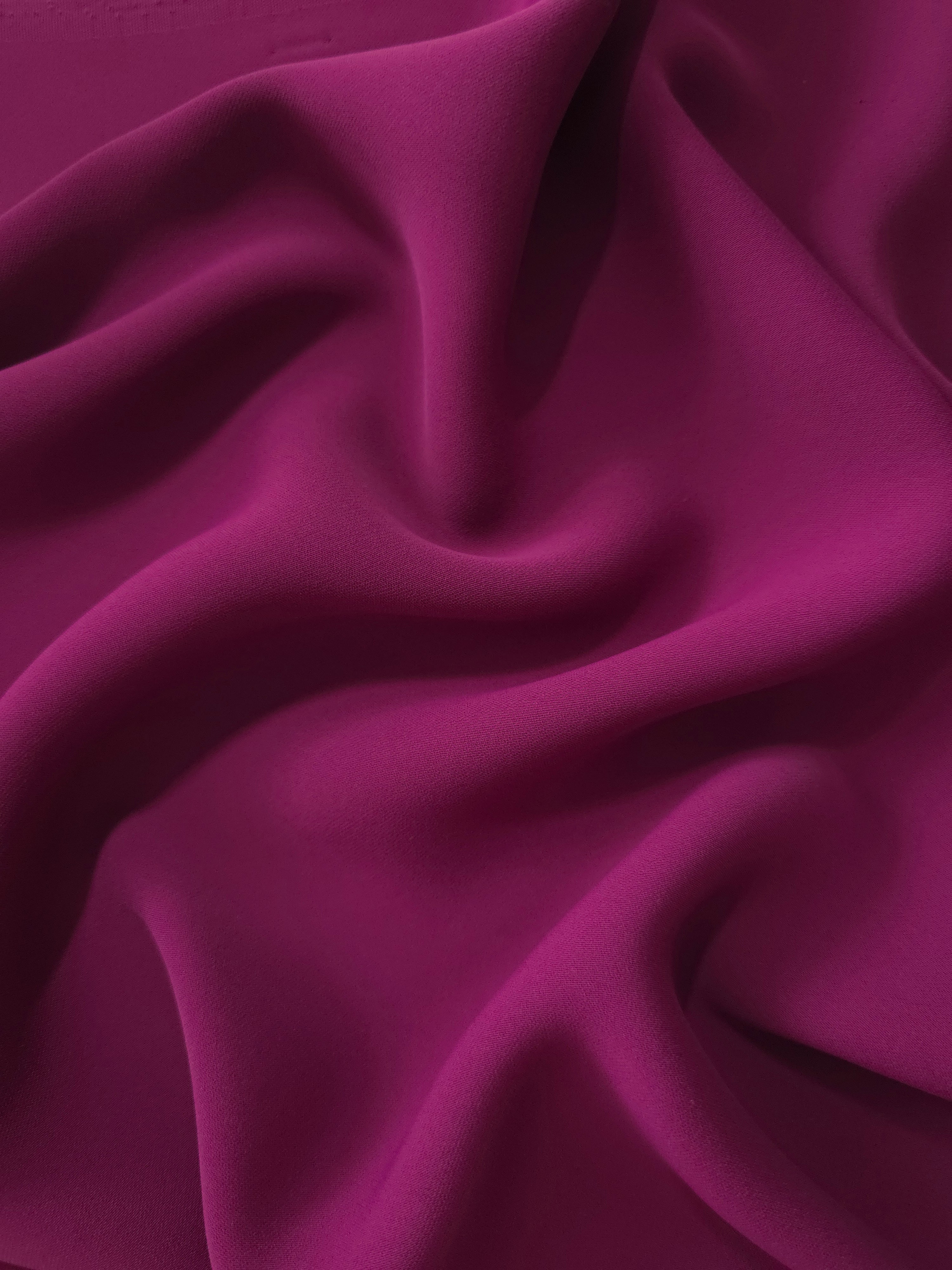 Draped folds of Deep Wine Berry polyester crepe showing fluid movement for dresses, skirts and elegant apparel