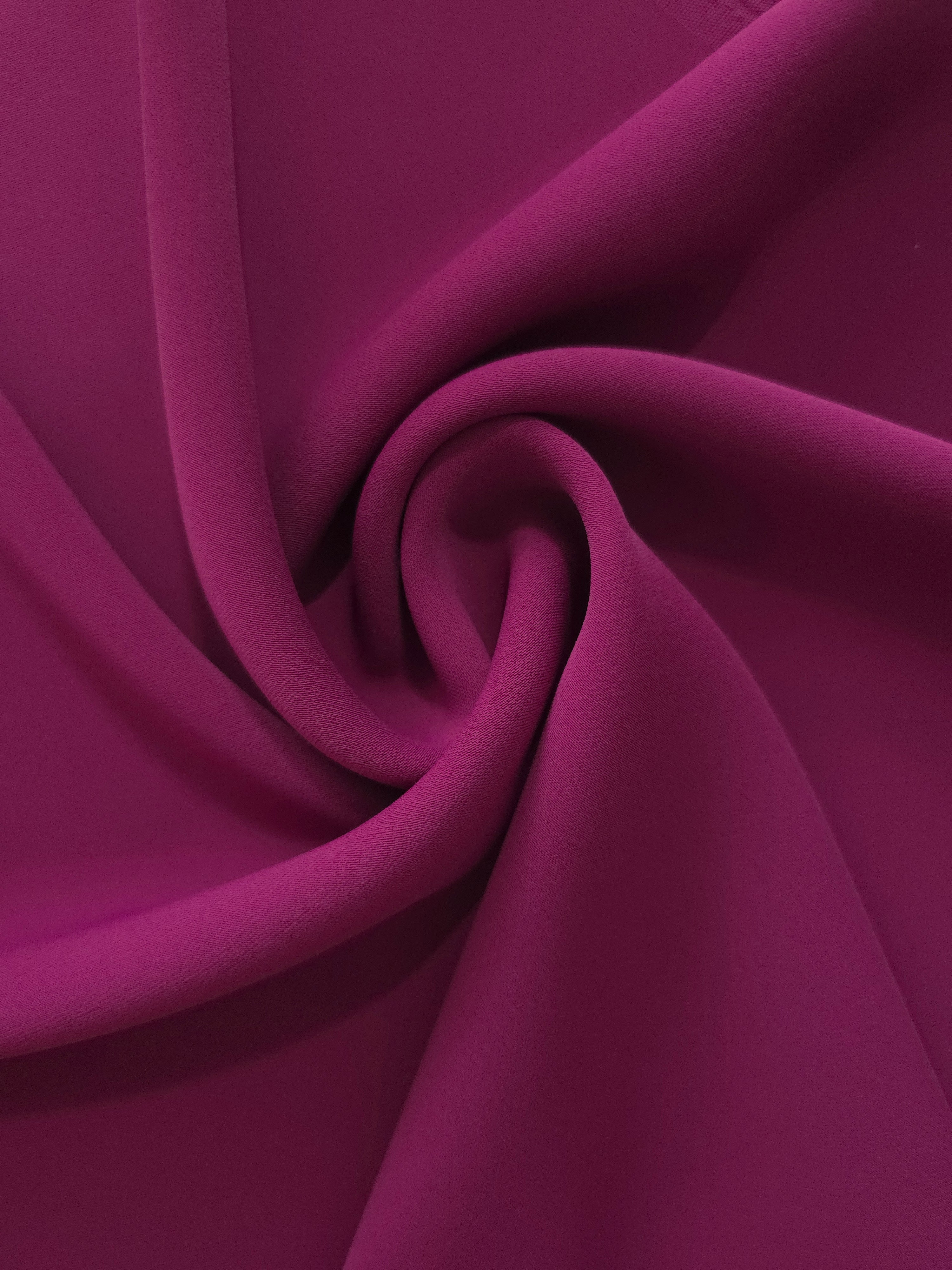Deep Wine Berry silky-feel polyester crepe styled in a swirl to show fluid dressmaking drape and movement