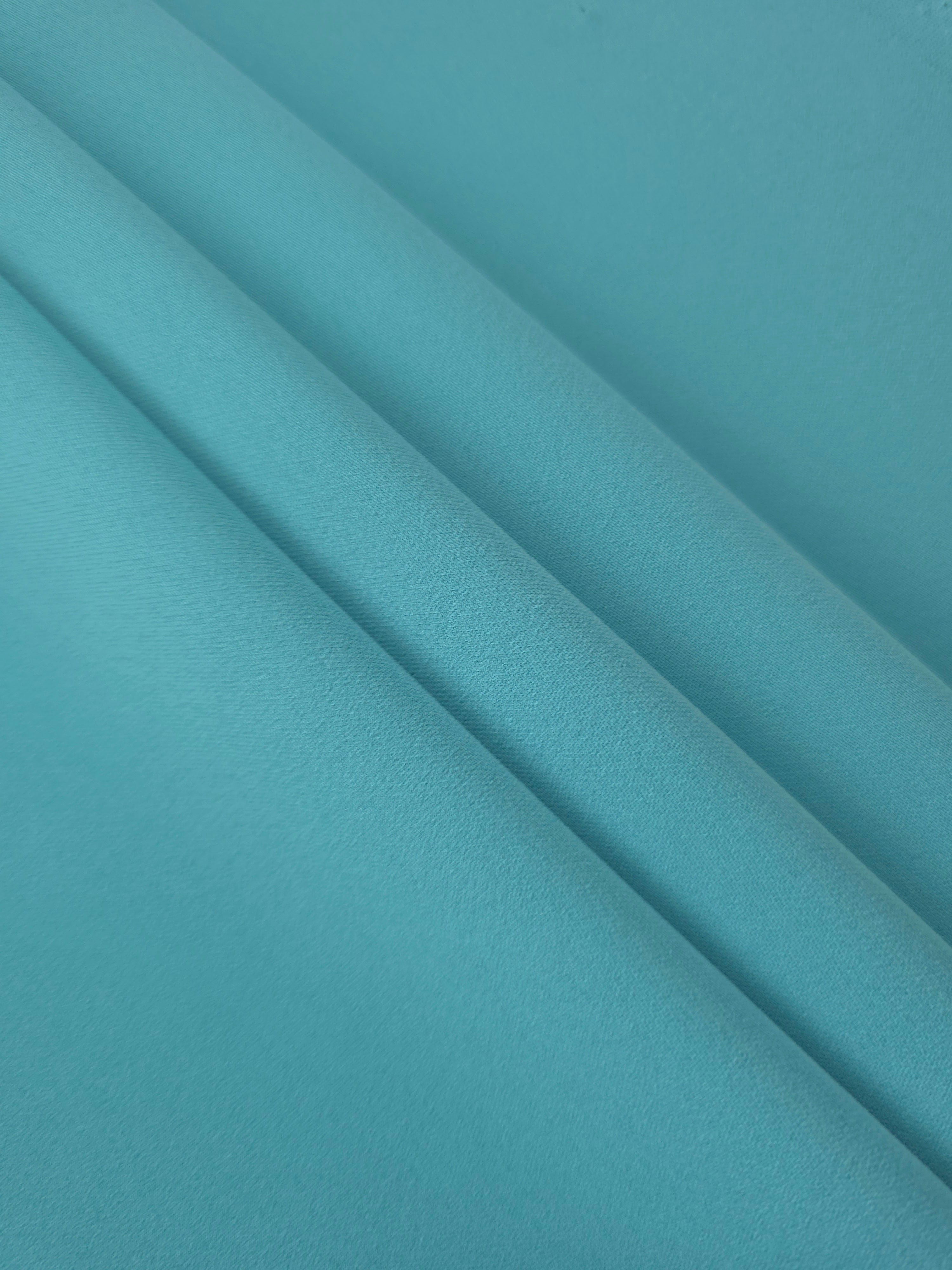 Layered Dusty Aqua Blue polyester crepe showing soft body and slight mechanical stretch for light tailoring