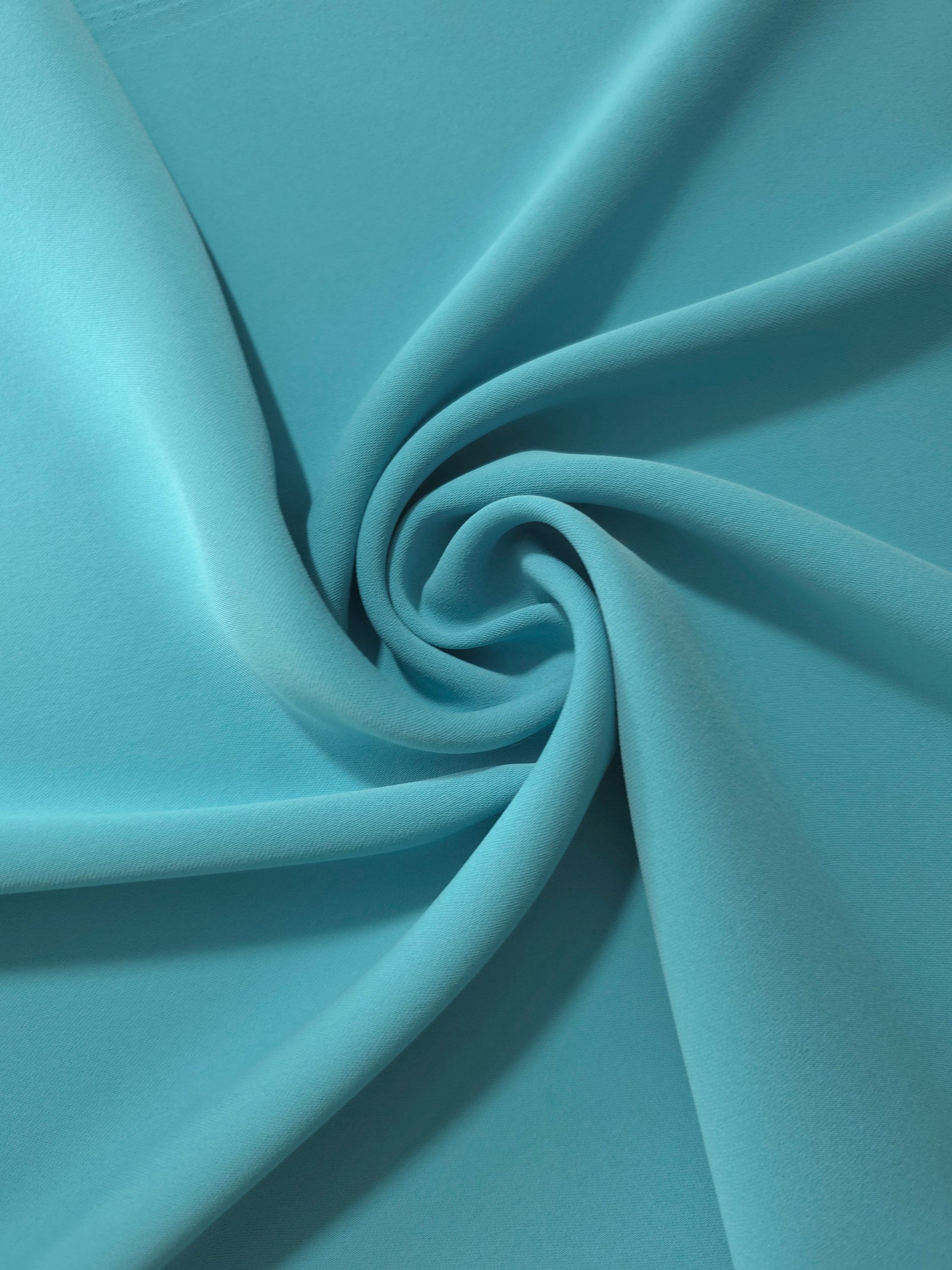 Circular drape of Dusty Aqua Blue polyester crepe showing flowing movement for occasion dresses and modest fashion