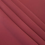 Layered folds of Dusty Burgundy 100% mechanical polyester crepe showing body and gentle construction stretch