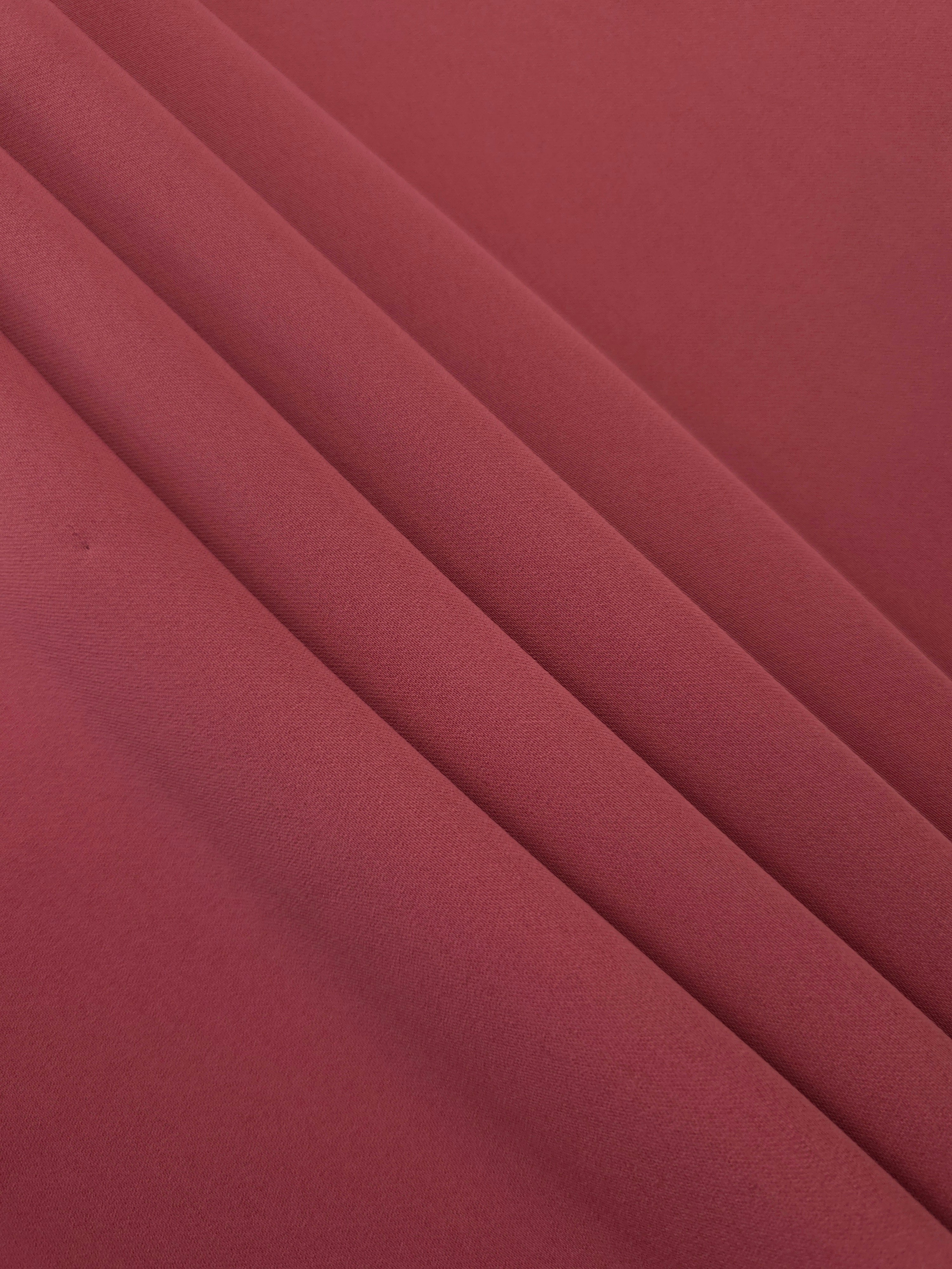 Layered folds of Dusty Burgundy 100% mechanical polyester crepe showing body and gentle construction stretch
