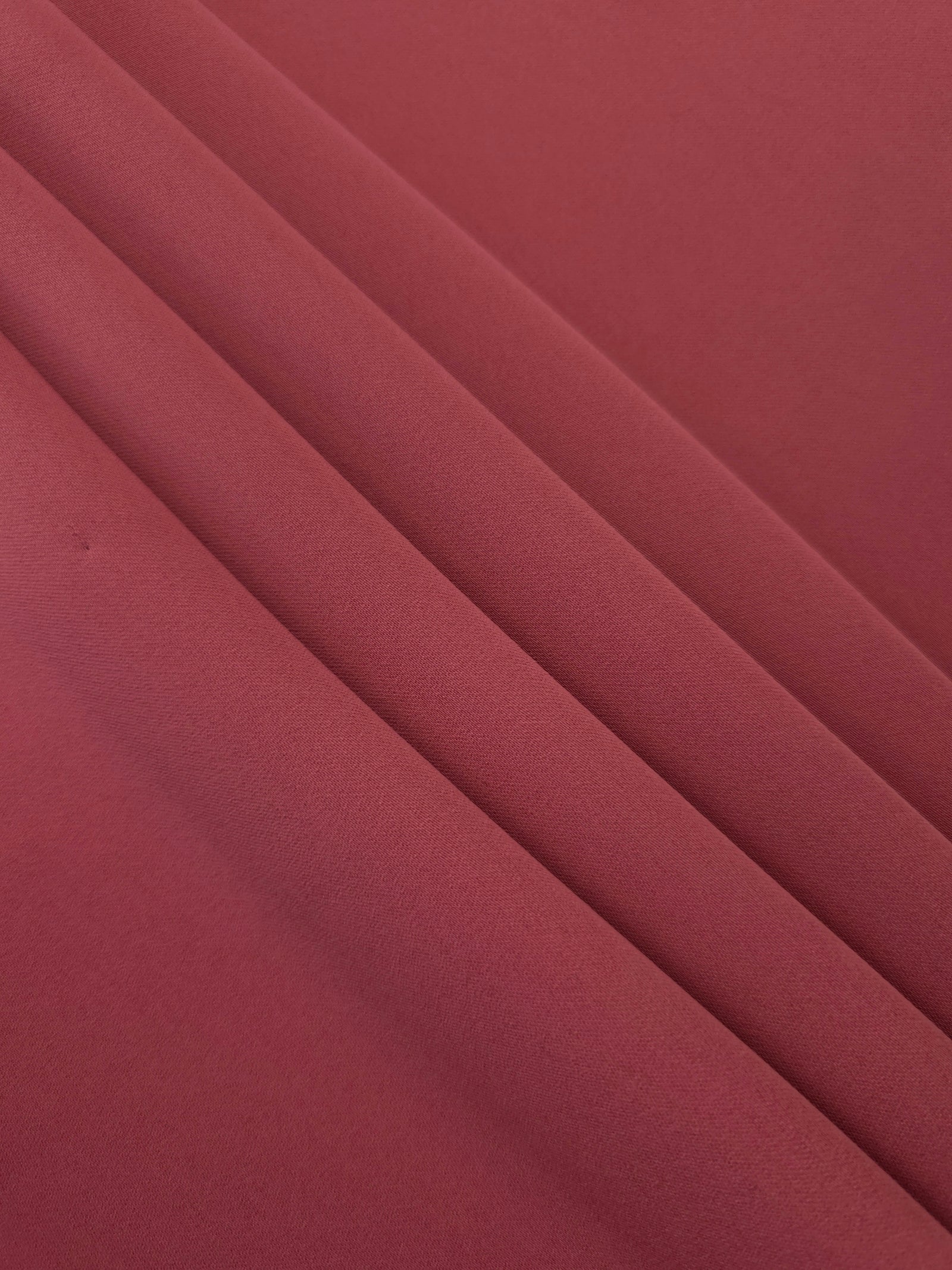 Layered folds of Dusty Burgundy 100% mechanical polyester crepe showing body and gentle construction stretch
