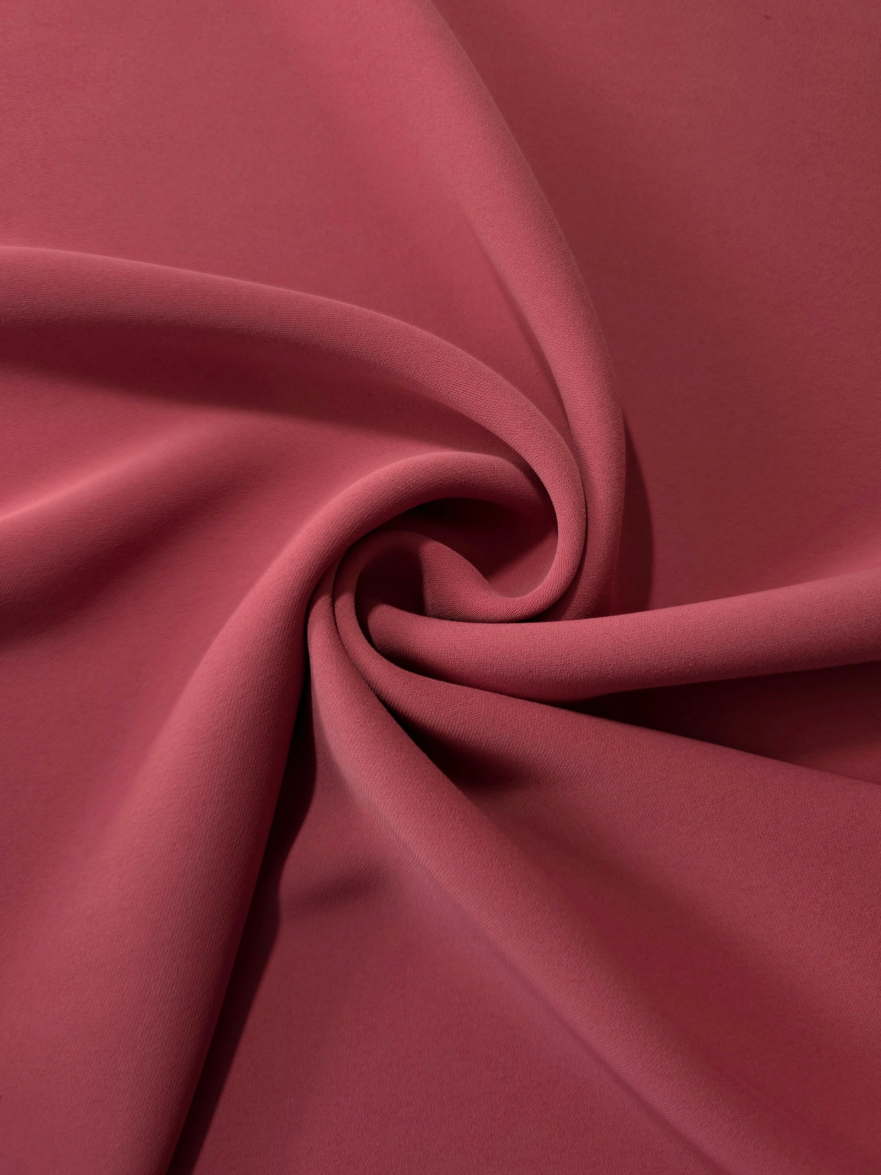 Dusty Burgundy opaque polyester crepe in a spiral drape, showing flowing form for skirts and modest garments