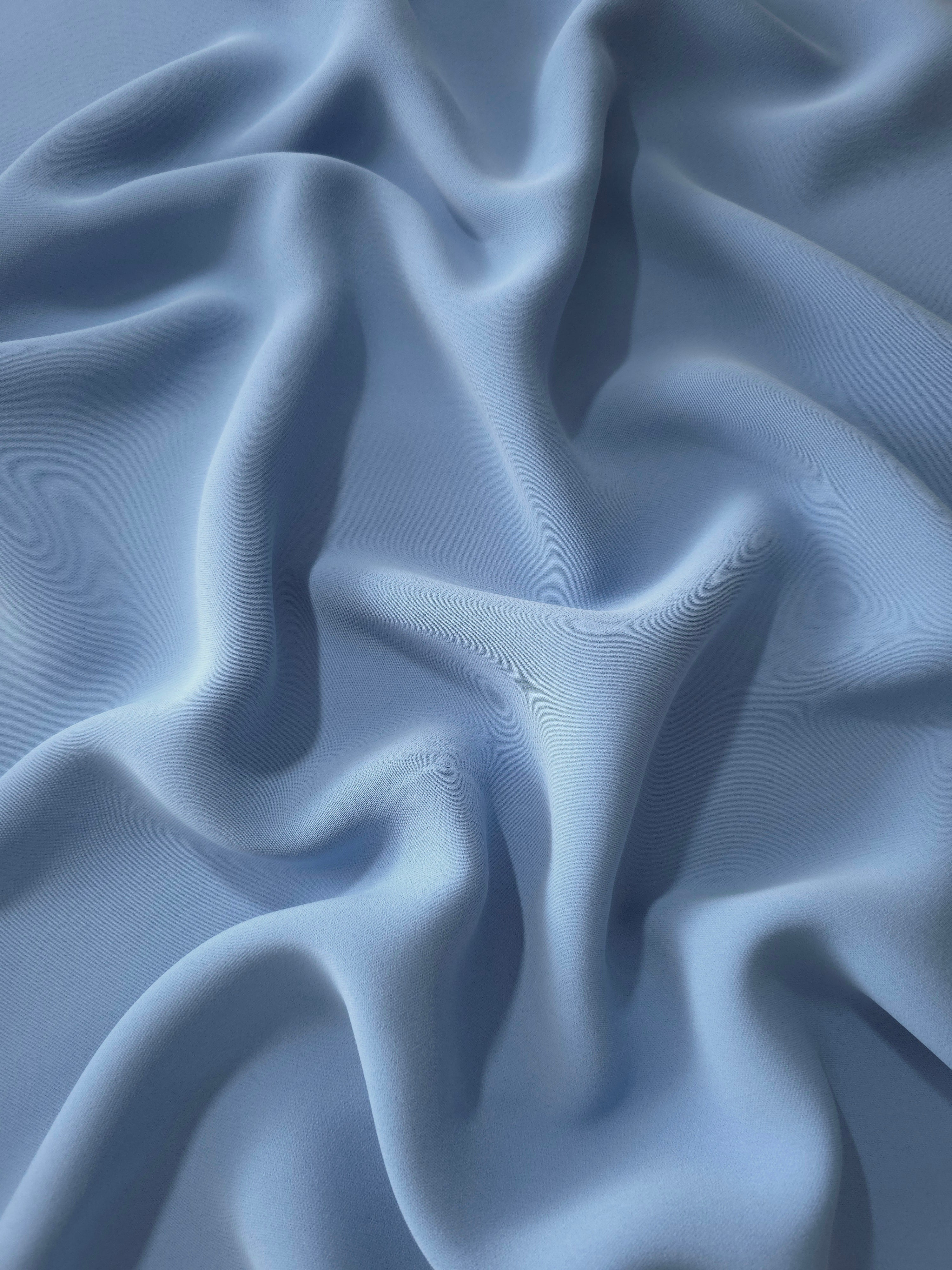 Fluid folds of Dusty Denim Blue polyester crepe, a flowing apparel fabric suited to eveningwear and skirts