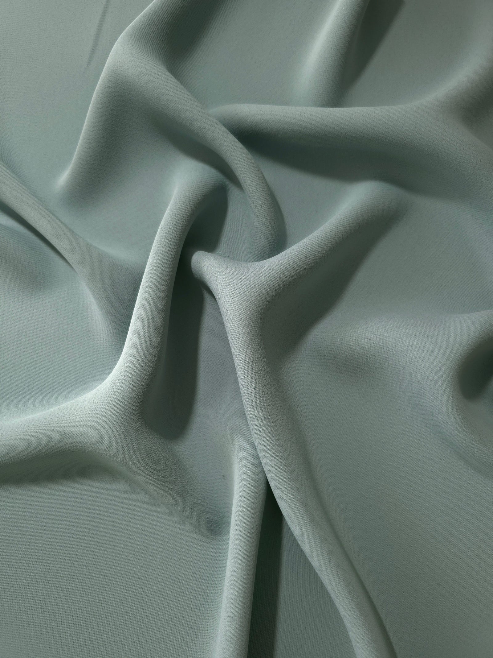 Draped Dusty Eucalyptus Green Korean polyester crepe showing opaque fluid folds for evening dresses and occasionwear