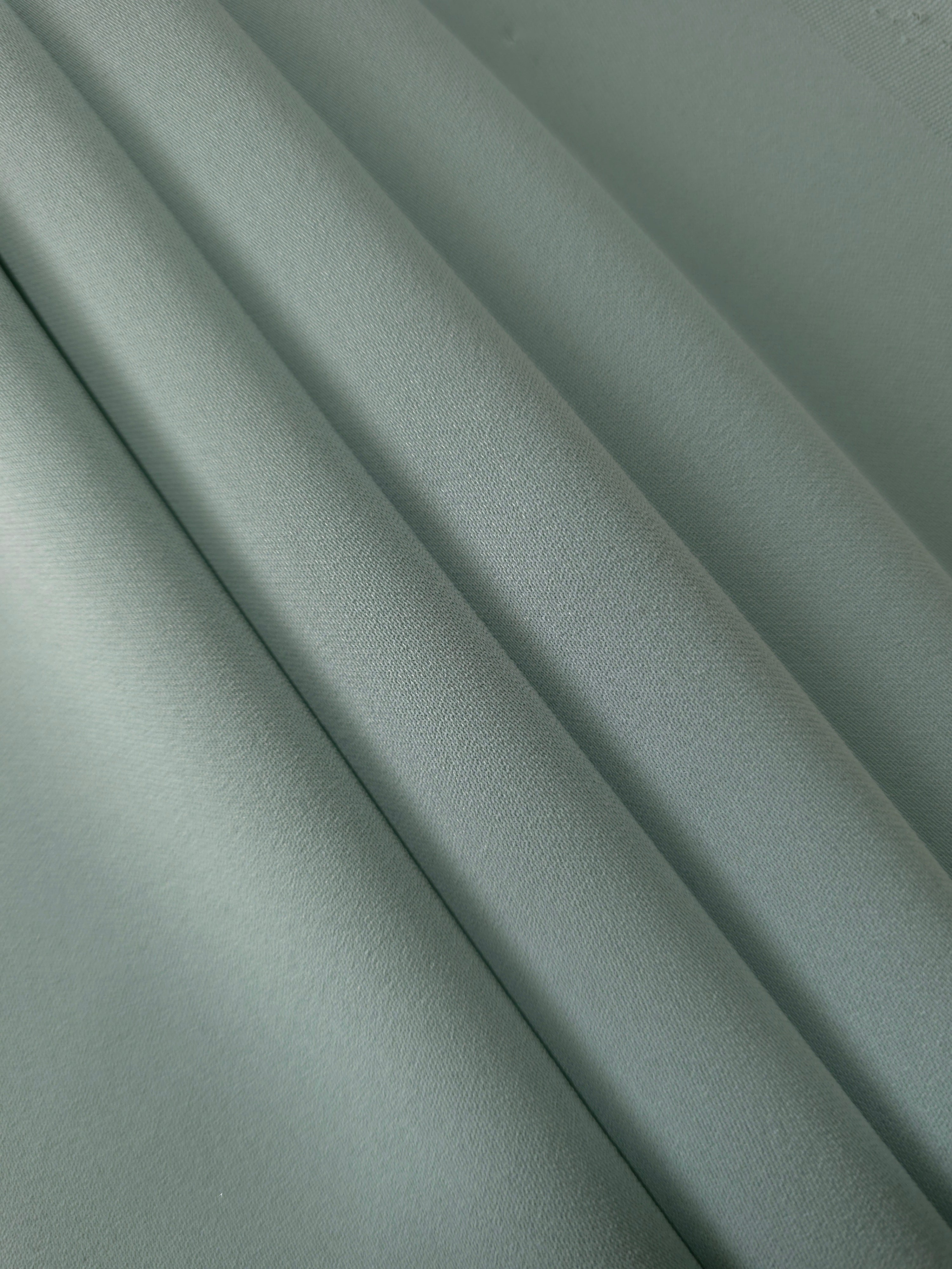 Layered Dusty Eucalyptus Green mechanical polyester crepe showing soft structure and slight mechanical stretch for tailoring