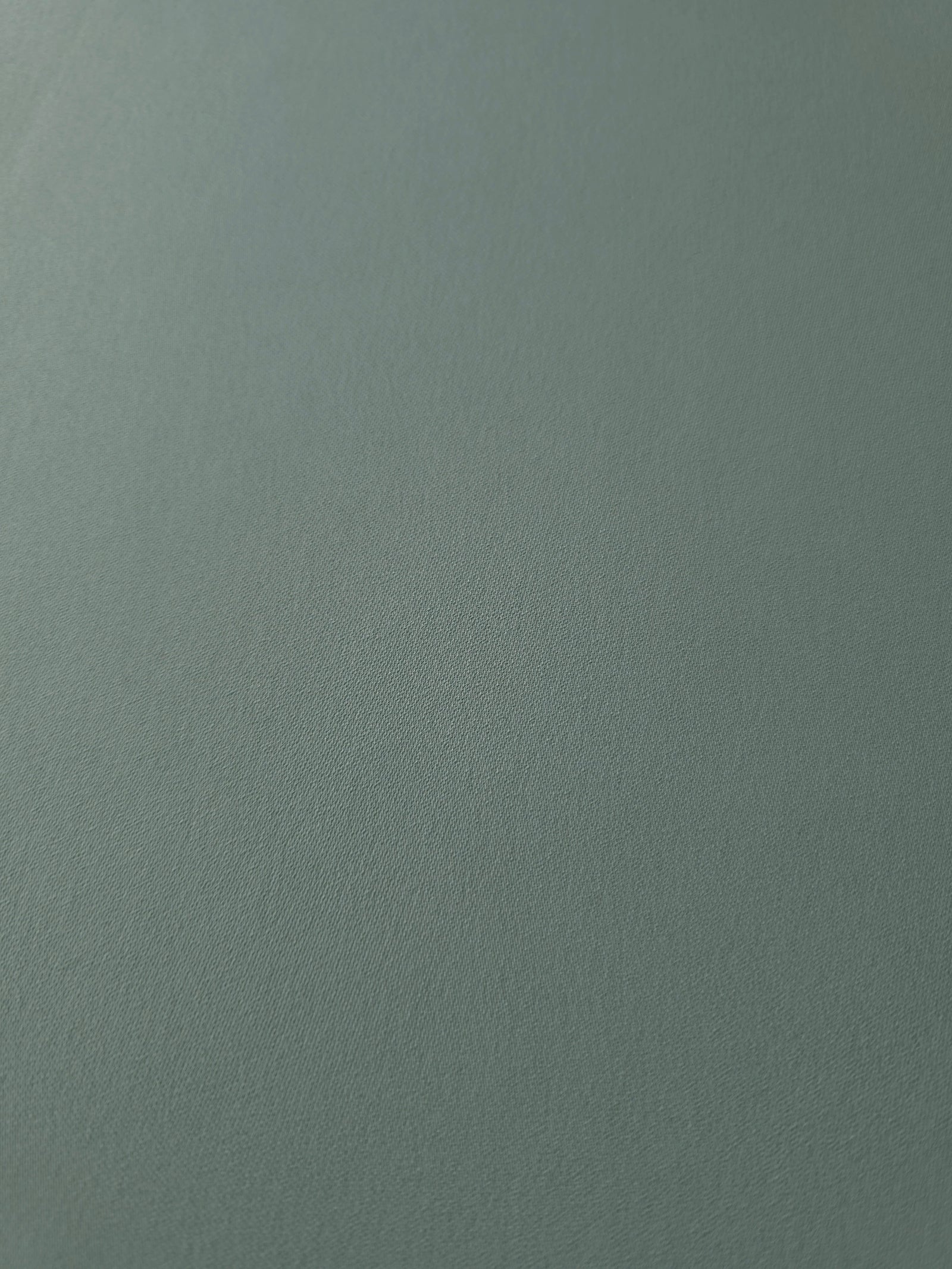 Close-up of Dusty Eucalyptus Green 100% mechanical polyester crepe showing fine woven texture and a silky-soft hand feel