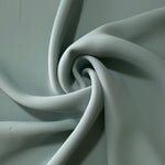 Dusty Eucalyptus Green polyester crepe arranged in a flowing swirl, showing drape used for abayas and modest fashion