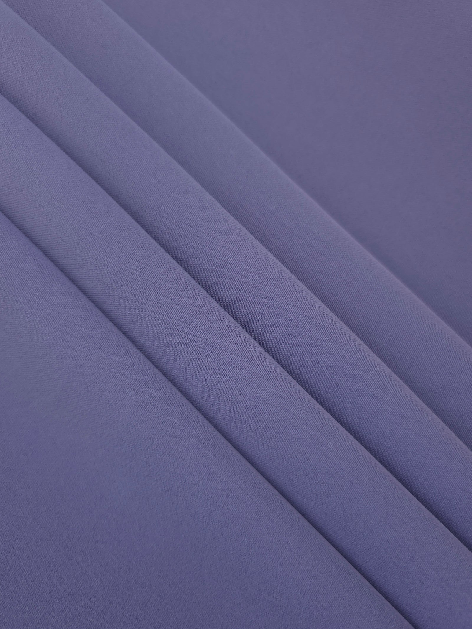 Layered folds of Dusty Indigo Blue 100% mechanical polyester crepe showing body and gentle construction stretch