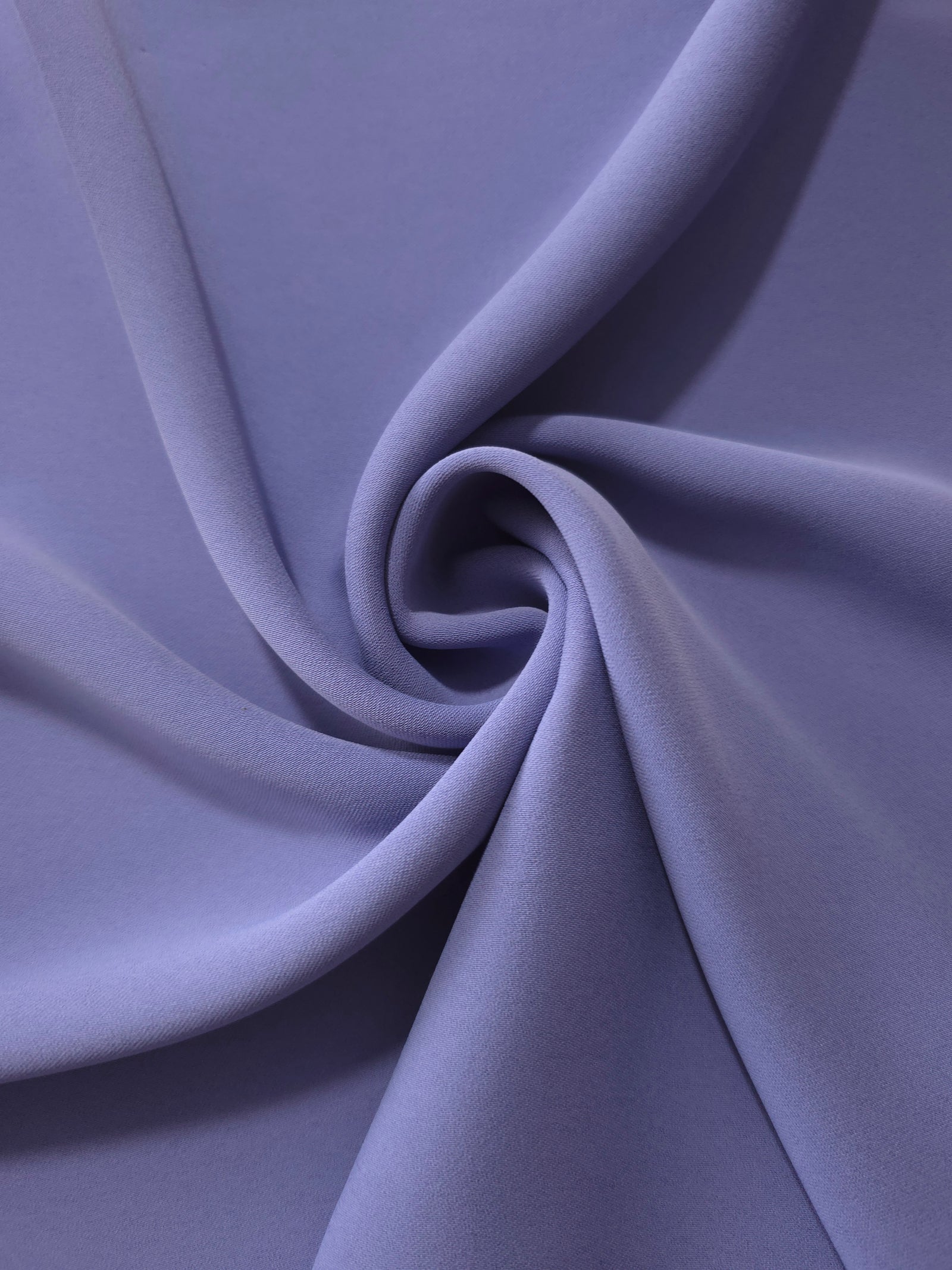 Dusty Indigo Blue opaque polyester crepe in a spiral drape, showing flowing form for skirts and modest garments