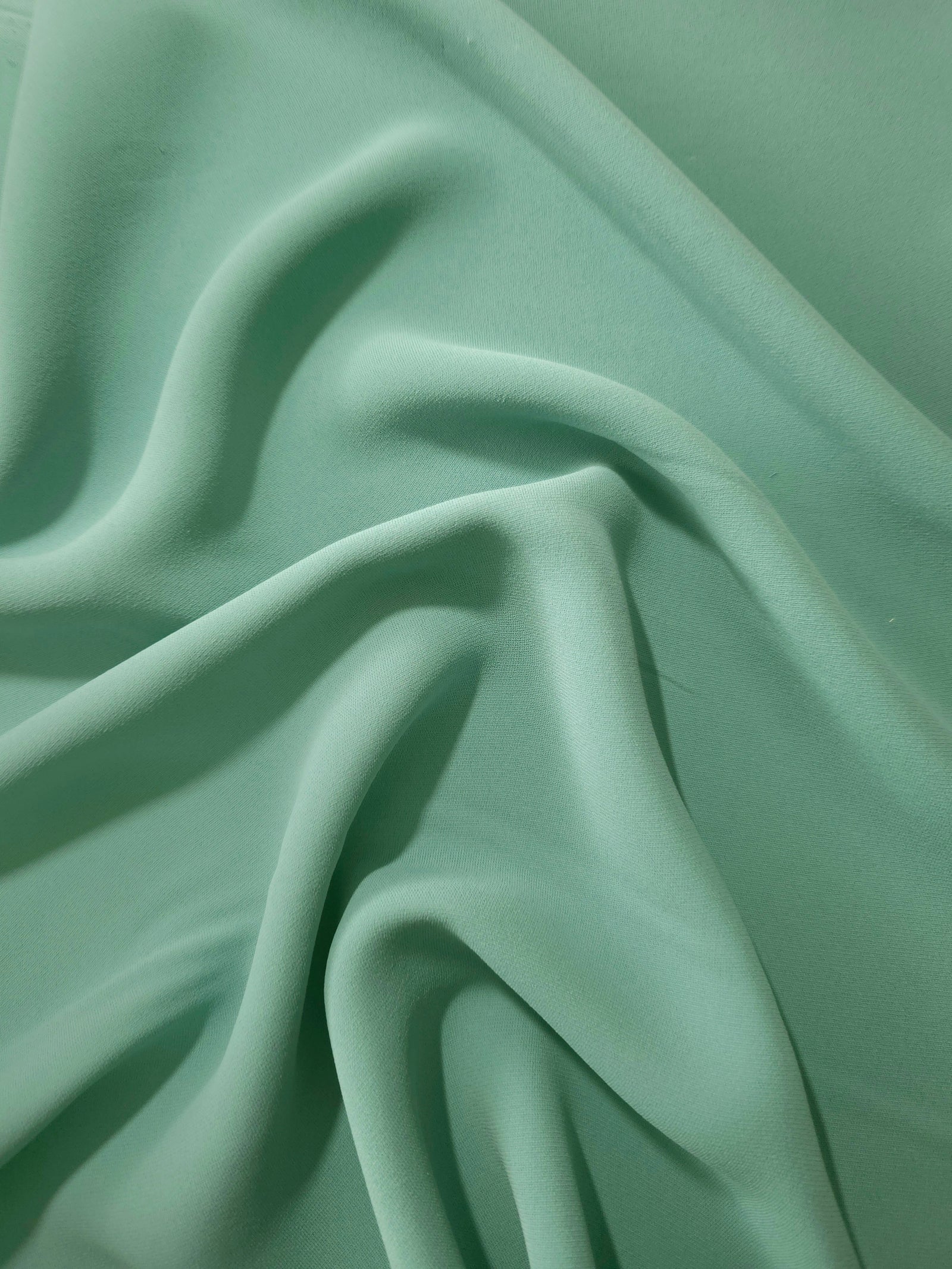 Dusty Mint Green Korean crepe displayed in fluid draped folds for eveningwear, skirts and flowing garments