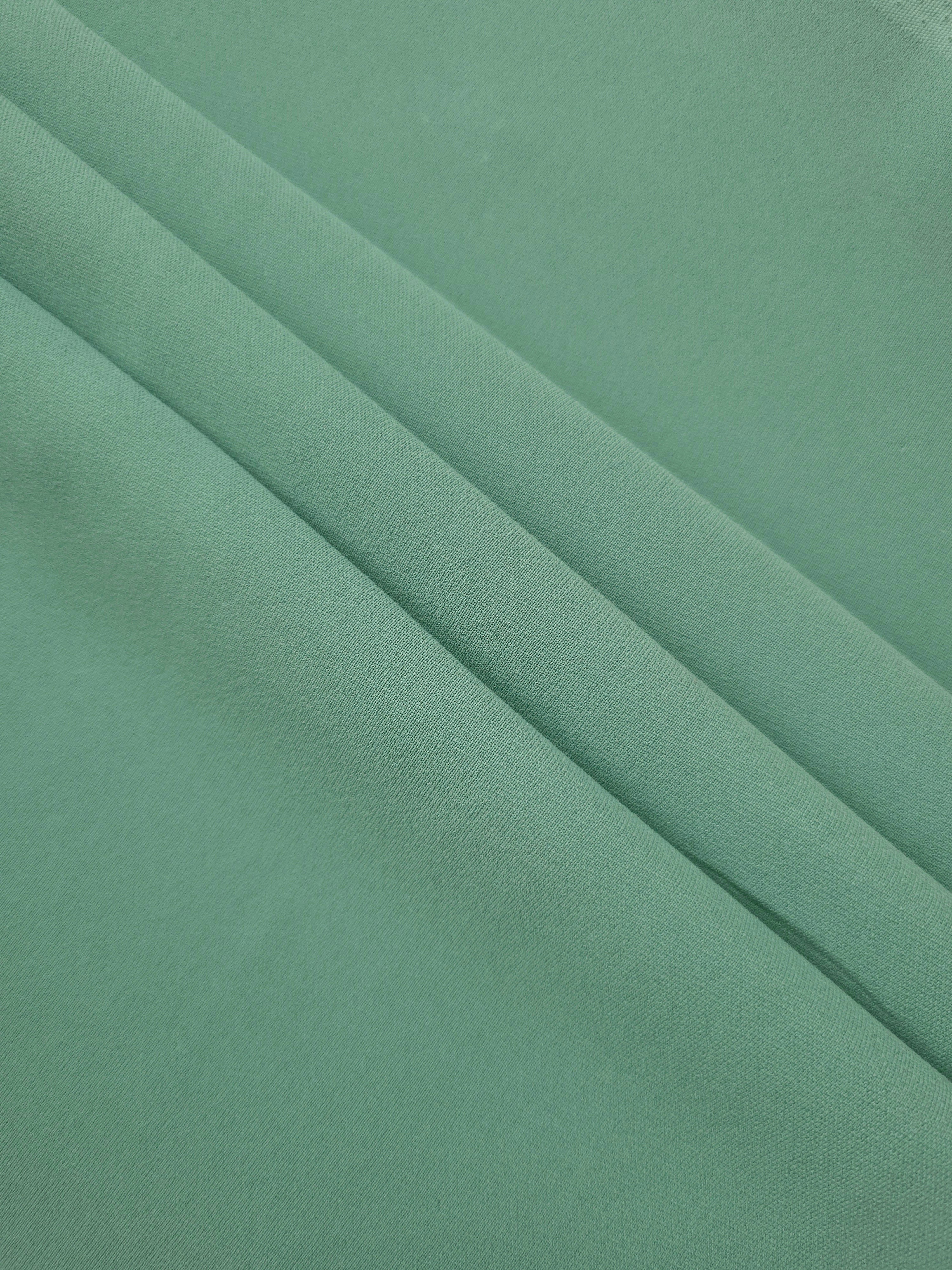 Dusty Mint Green mechanical polyester crepe in layered folds, showing gentle stretch and structure for dressmaking