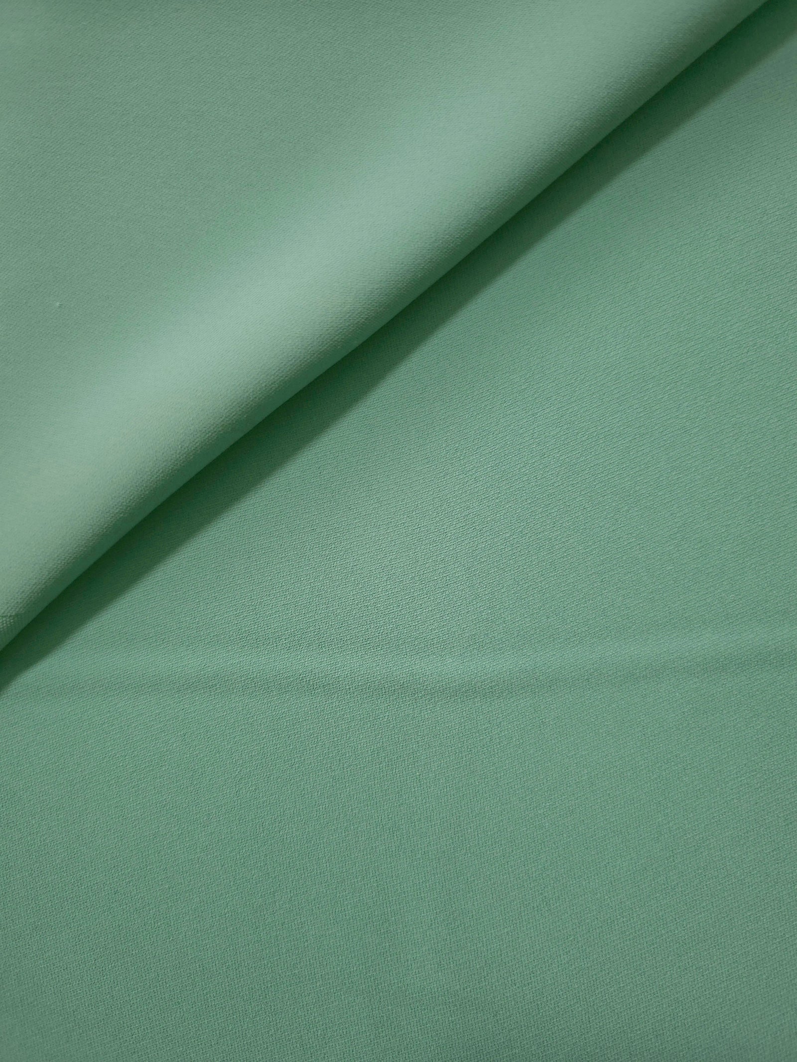 Dusty Mint Green polyester crepe gathered into a soft fold, showing fluid drape for dresses and blouse making
