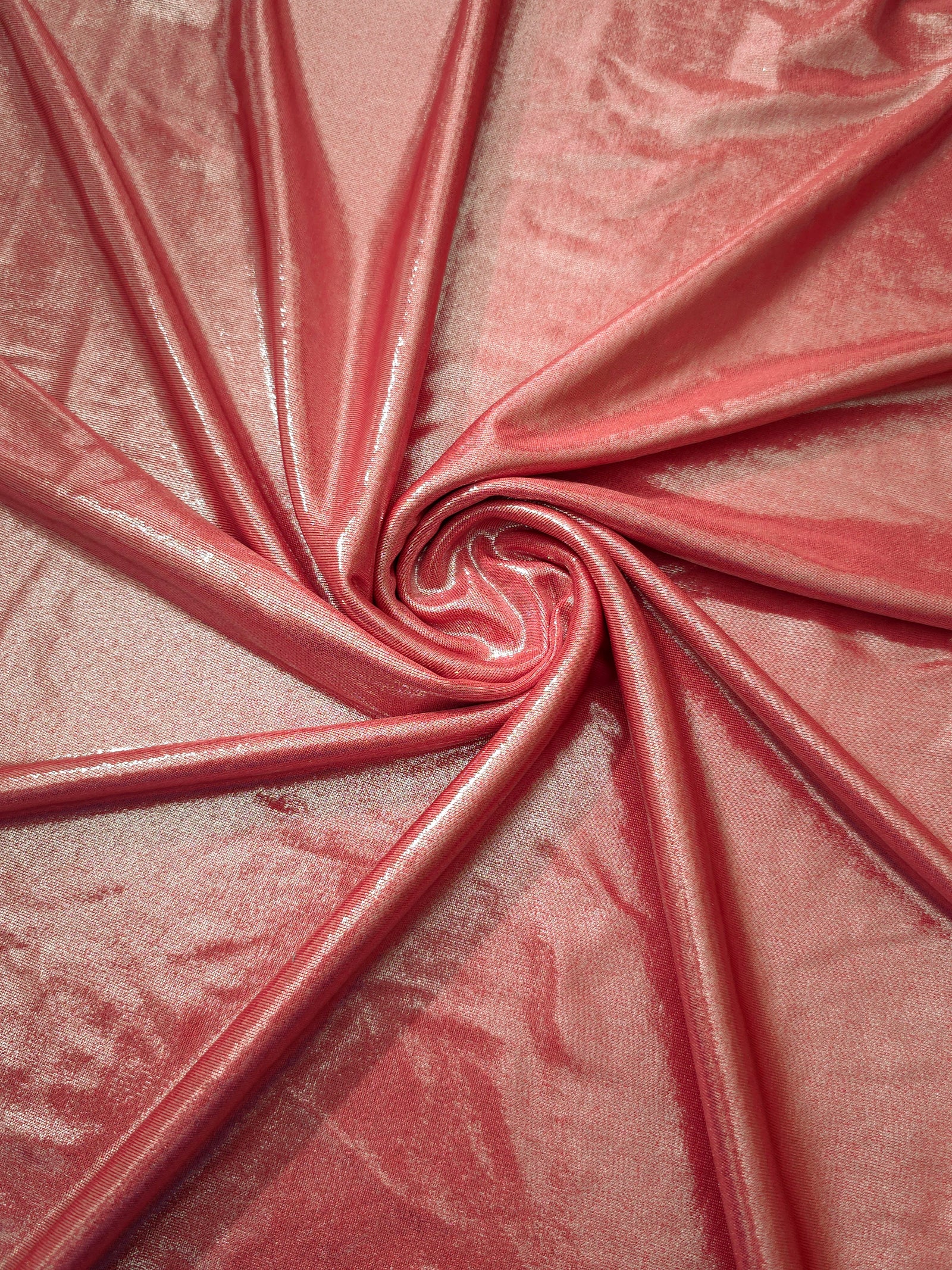 Flowing swirl of Dusty Peach Pink metallic stretch fabric, showing dynamic foil reflection for stagewear, skirts and creative fashion