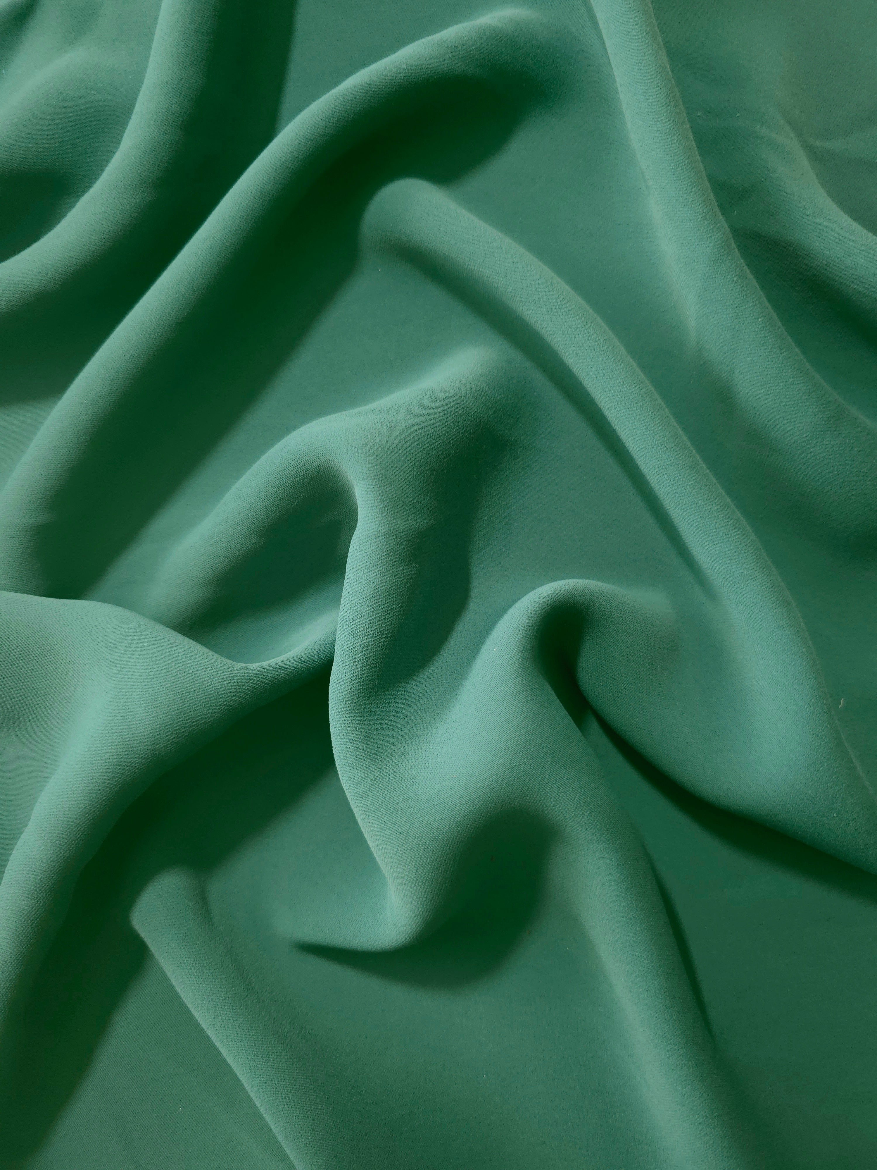 Dusty Pine Green Italian crepe in long draped folds, showing flowing coverage for abayas and modest garments