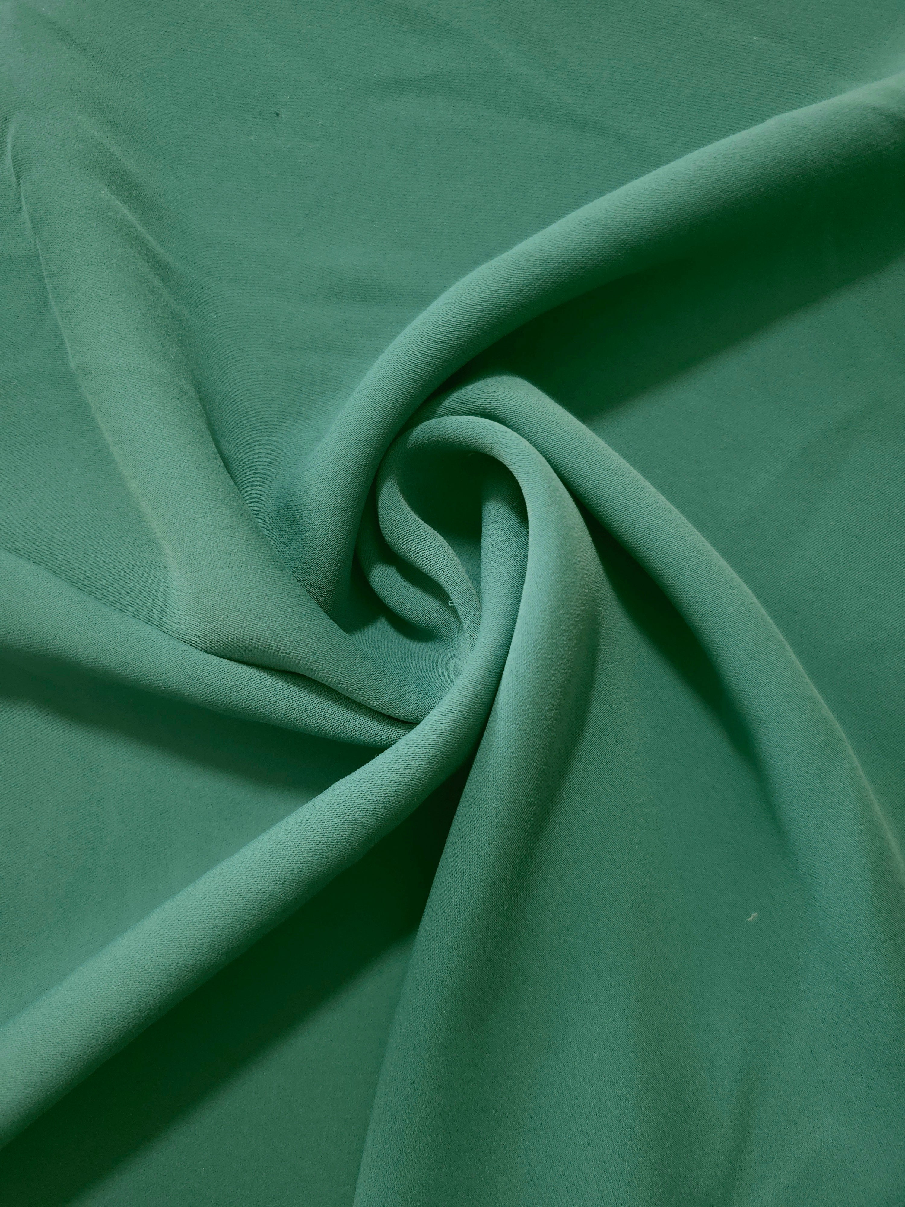 Swirled Dusty Pine Green polyester crepe showing supple movement and soft drape for dresses and occasionwear