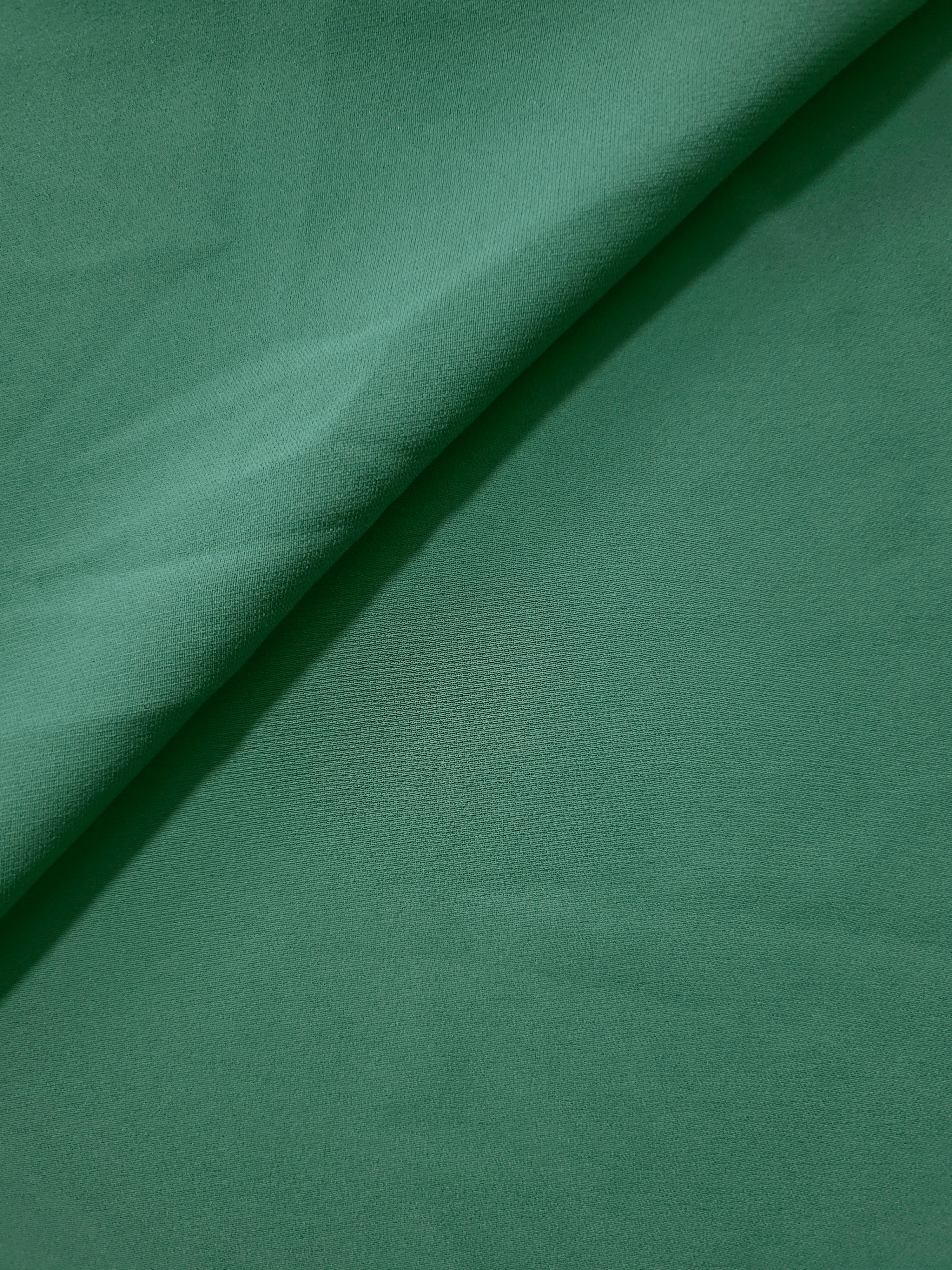Soft fold of Dusty Pine Green polyester crepe showing fluid dressmaking drape for dresses, skirts and blouses