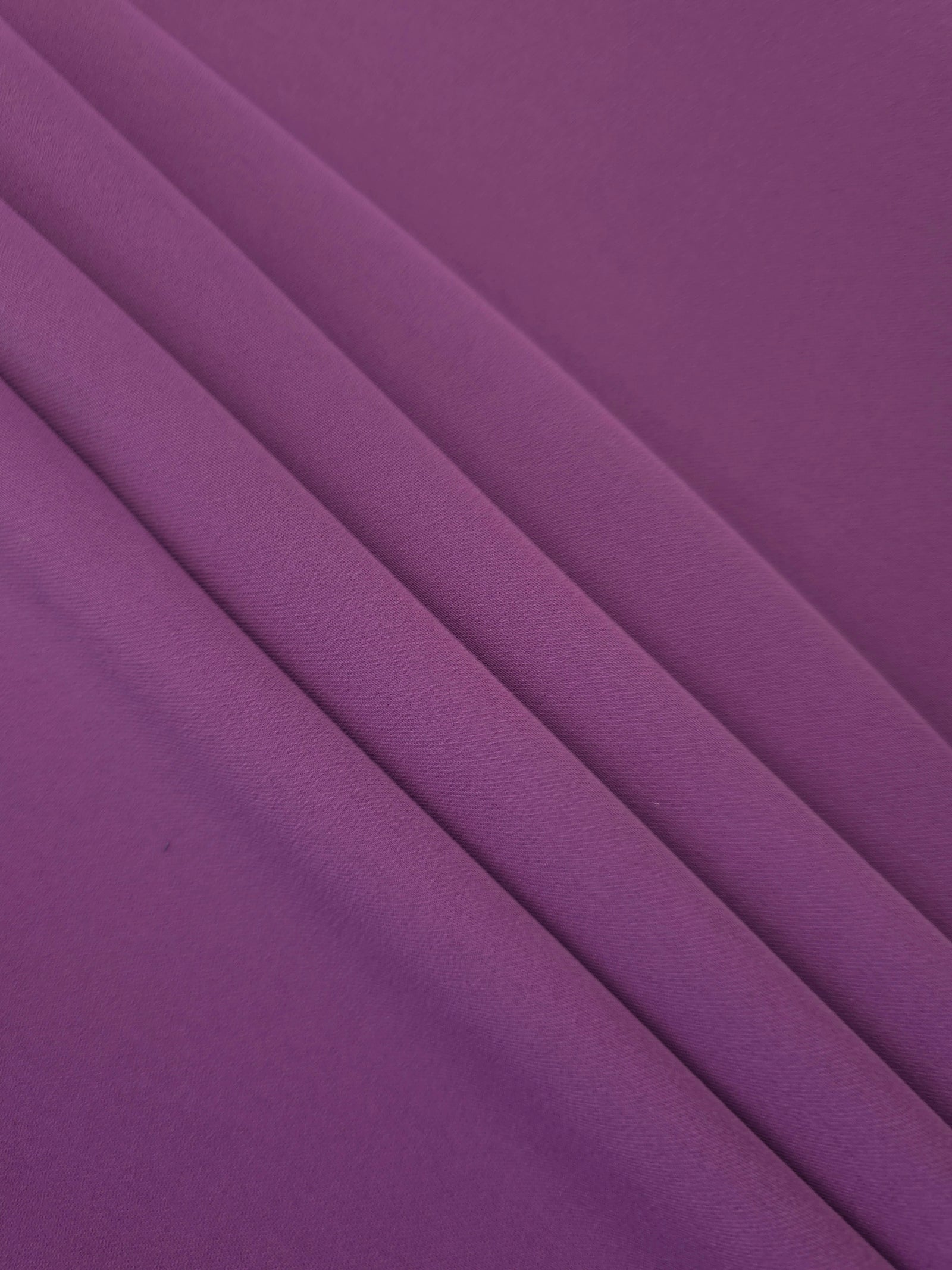 Flowing swirl of Dusty Plum Korean polyester crepe showing soft drape for blouses, dresses and abayas