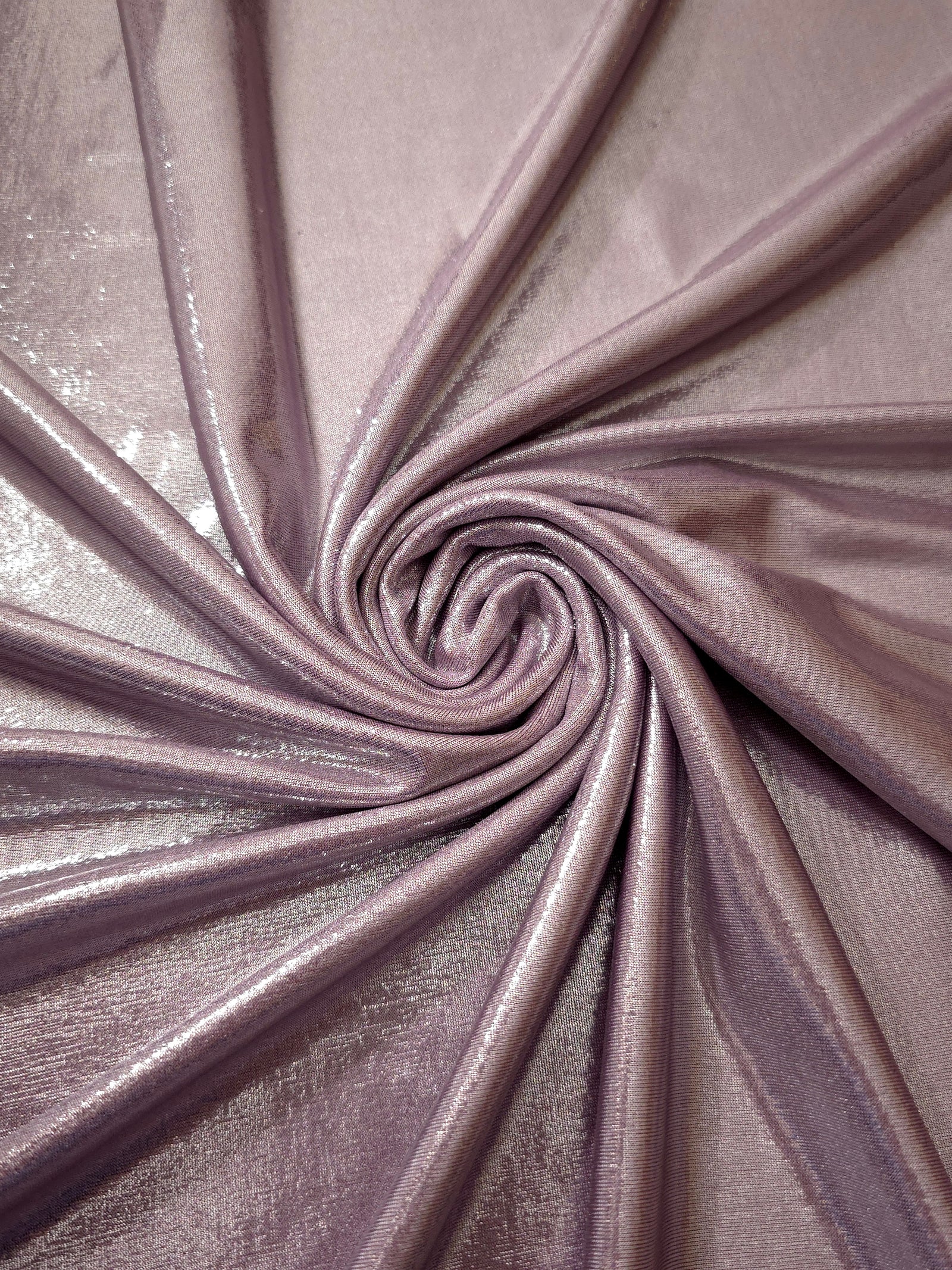 Dusty Rose Mauve metallic stretch fabric in a flowing swirl, emphasizing foil shimmer and drape for partywear and statement fashion