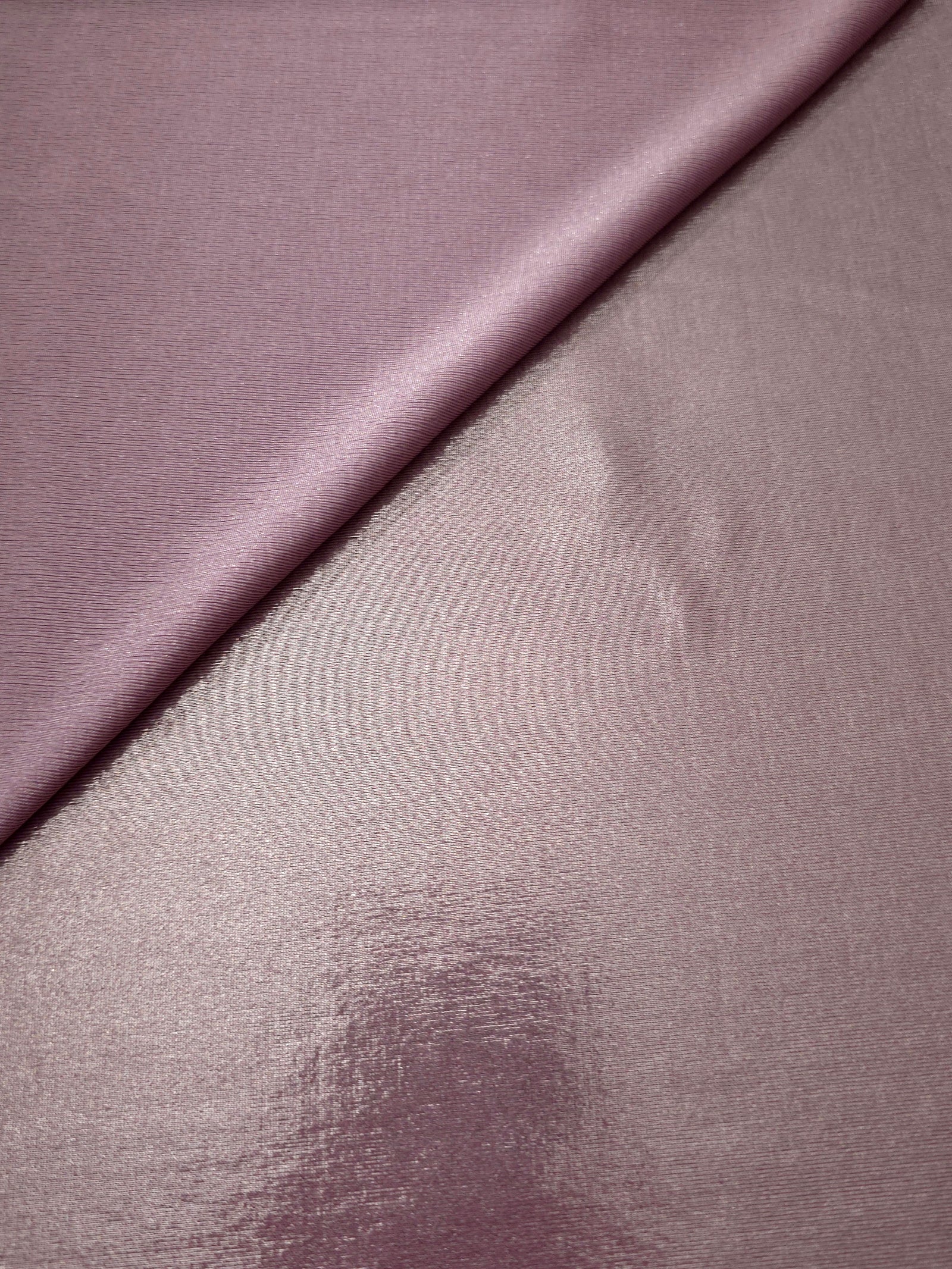 Dusty Rose Mauve foiled stretch fabric in a gentle fold, showing metallic shimmer and flexibility for partywear and performance fashion
