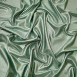 Draped Dusty Sage Green metallic foiled spandex showing reflective folds and flexible flow for dresses, stagewear and occasion looks