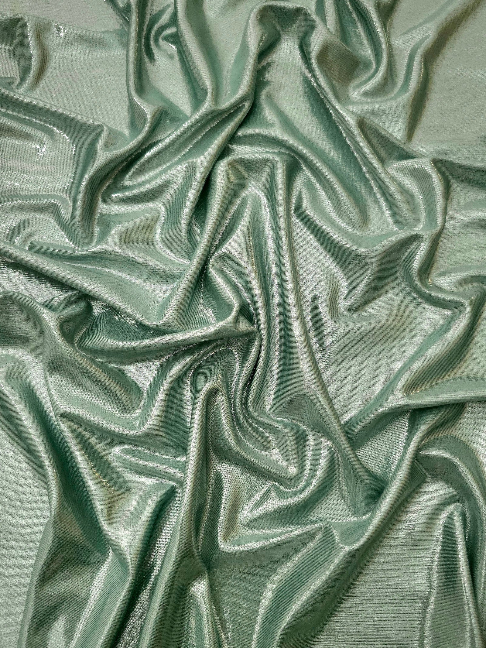 Draped Dusty Sage Green metallic foiled spandex showing reflective folds and flexible flow for dresses, stagewear and occasion looks