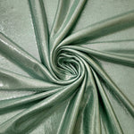 Dusty Sage Green shimmer foiled stretch fabric arranged in a swirl, highlighting movement and reflective finish for performancewear