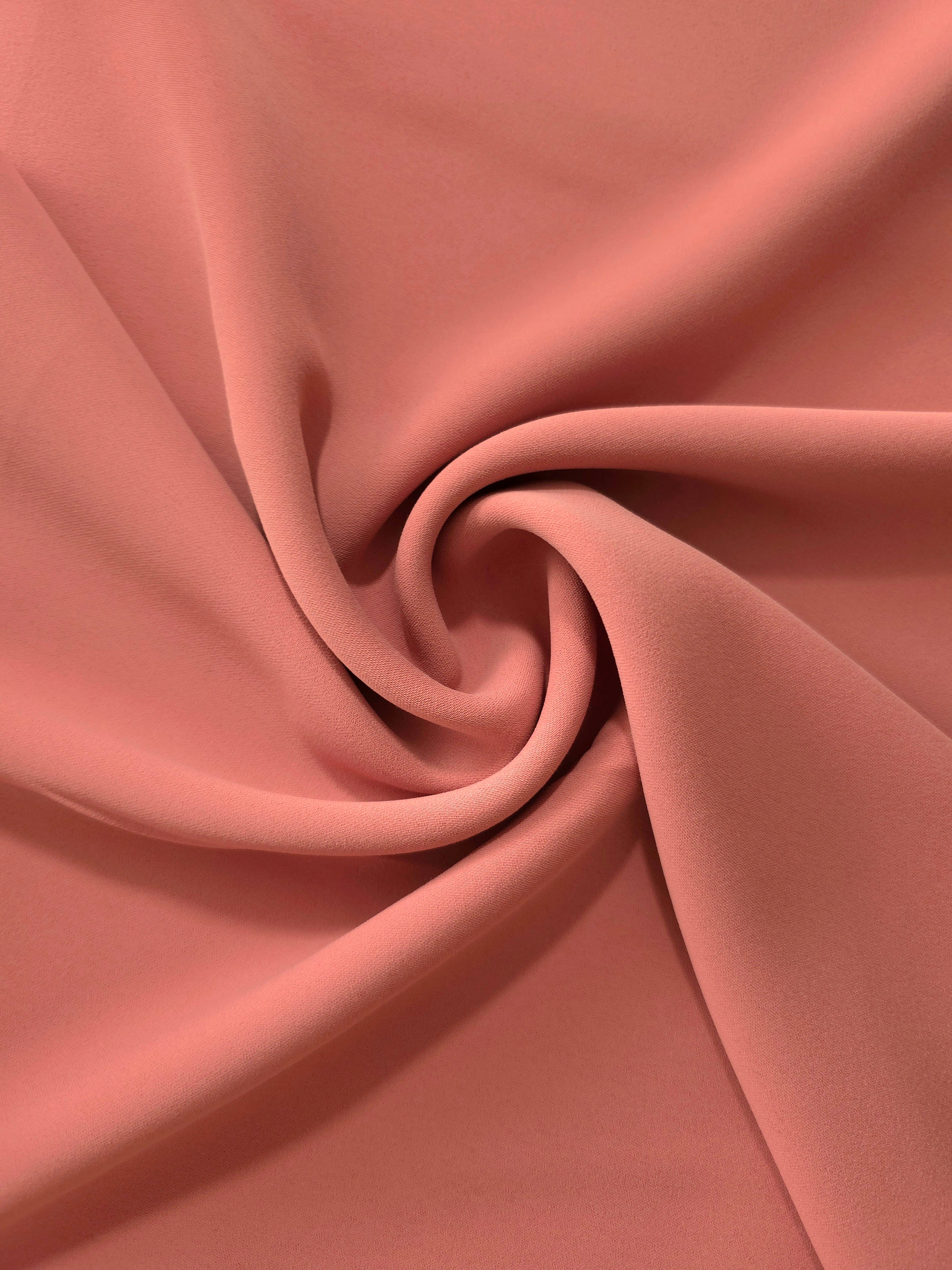Dusty Terracotta silky-feel polyester crepe styled in a swirl to show fluid dressmaking drape and movement