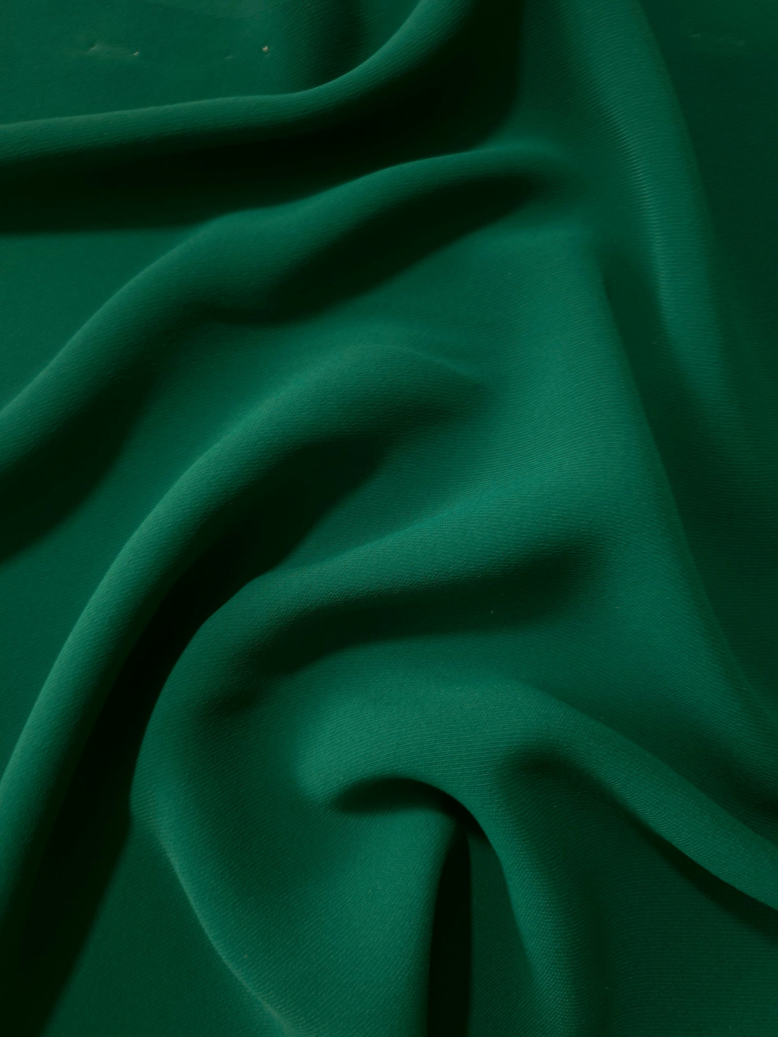 Forest Green Korean crepe displayed in fluid draped folds for eveningwear, skirts and flowing garments
