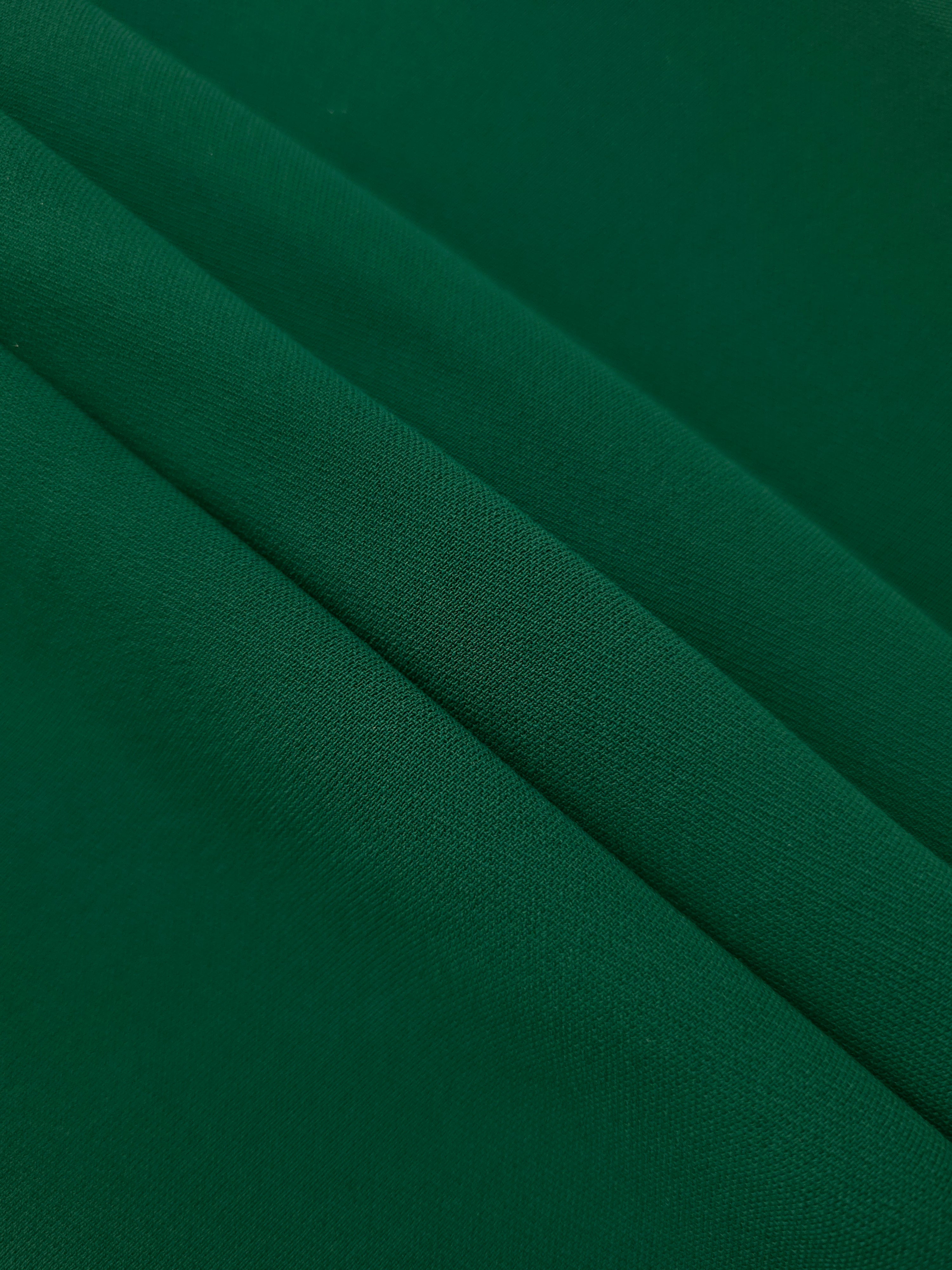 Forest Green mechanical polyester crepe in layered folds, showing gentle stretch and structure for dressmaking